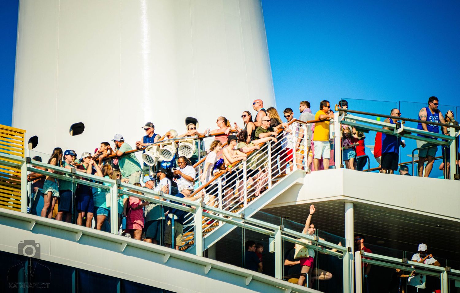 A panoramic view of people gathered on multiple levels of an outdoor stairway against a bright blue sky.