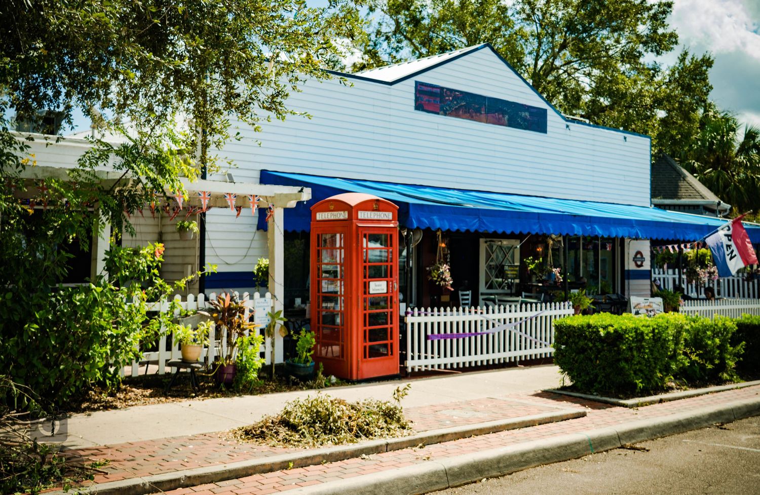 Charming blue and white storefront with red British phone booth and white picket fence.