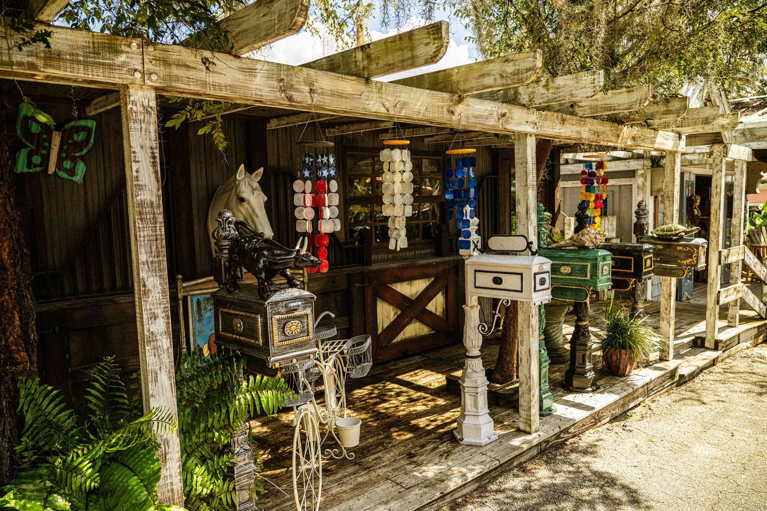 Rustic outdoor market stall with vintage mailboxes and decorative items displayed under a wooden pergola.