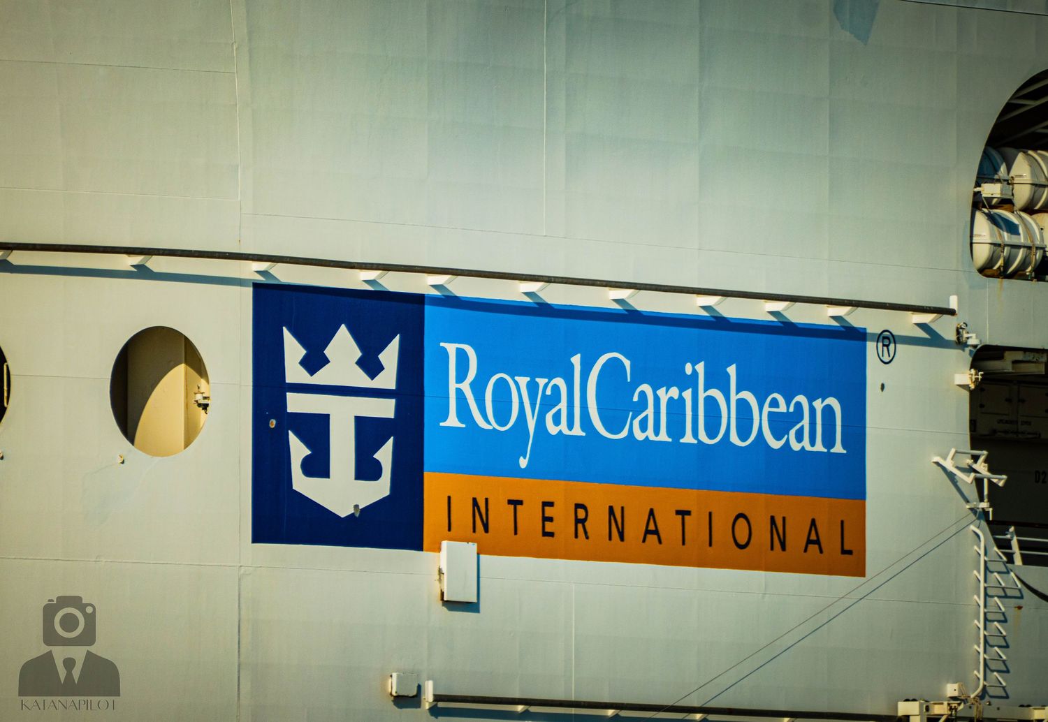 A Royal Caribbean International cruise line logo and banner mounted on a light-colored wall.