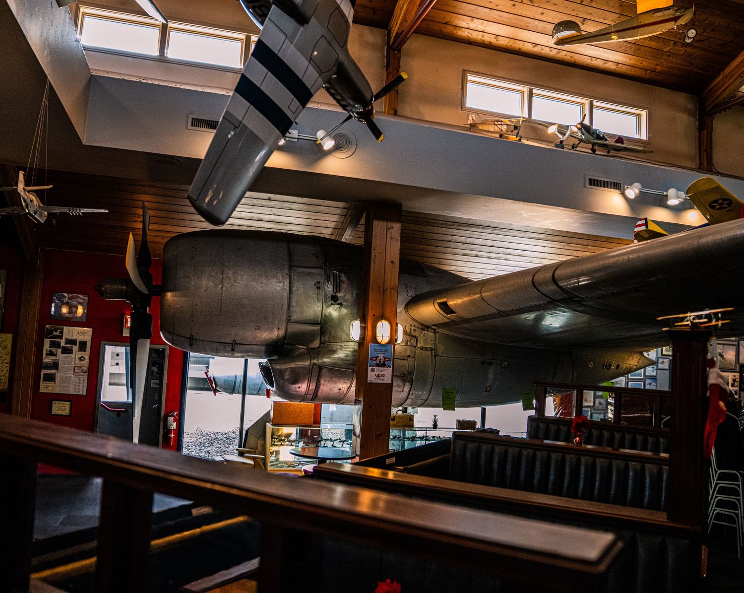 Interior of a rustic restaurant with wooden beams, track lighting, and dark booth seating in warm ambient lighting.