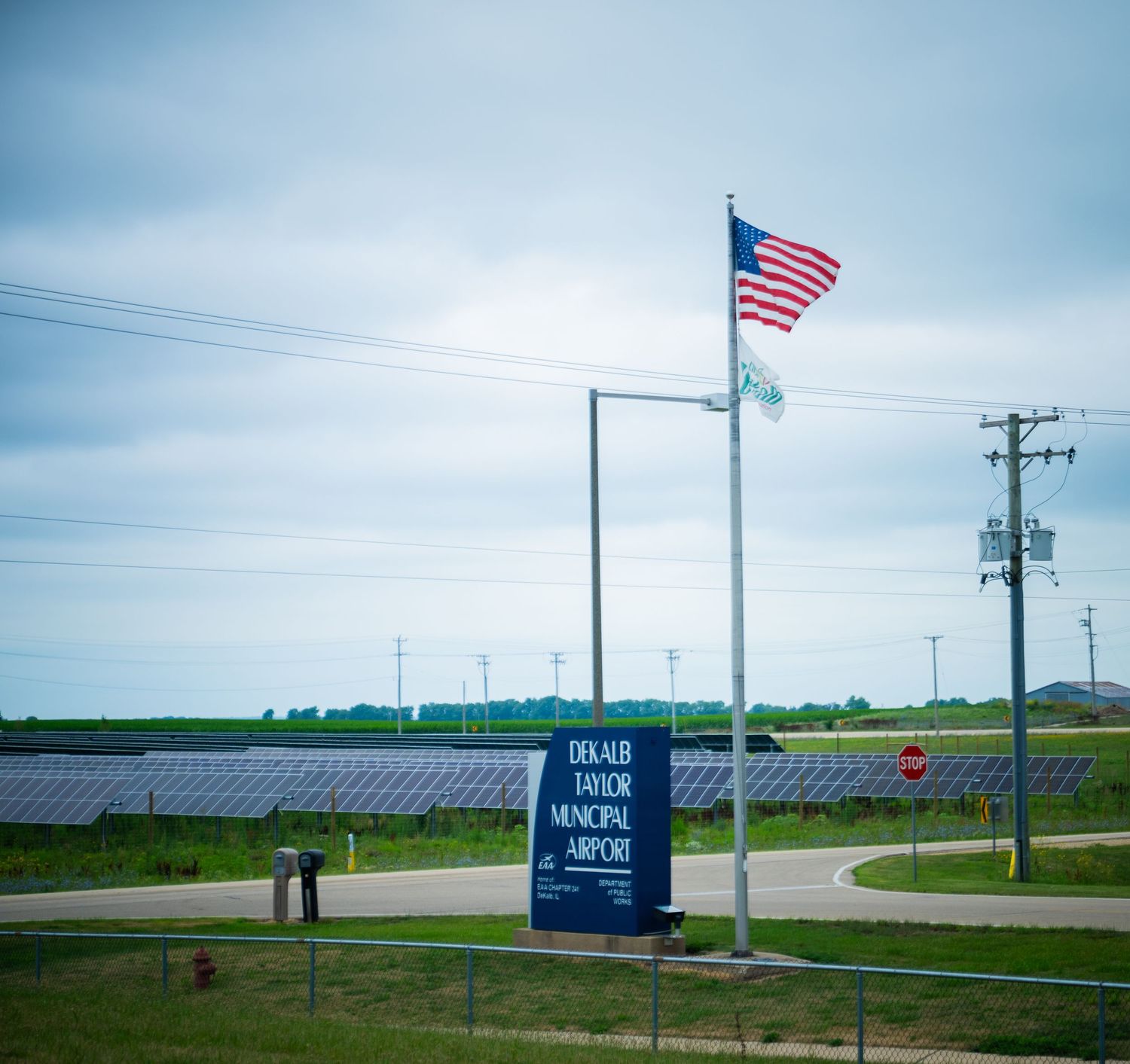 Rural airfield with American flags and solar panel installation visible in the distance.