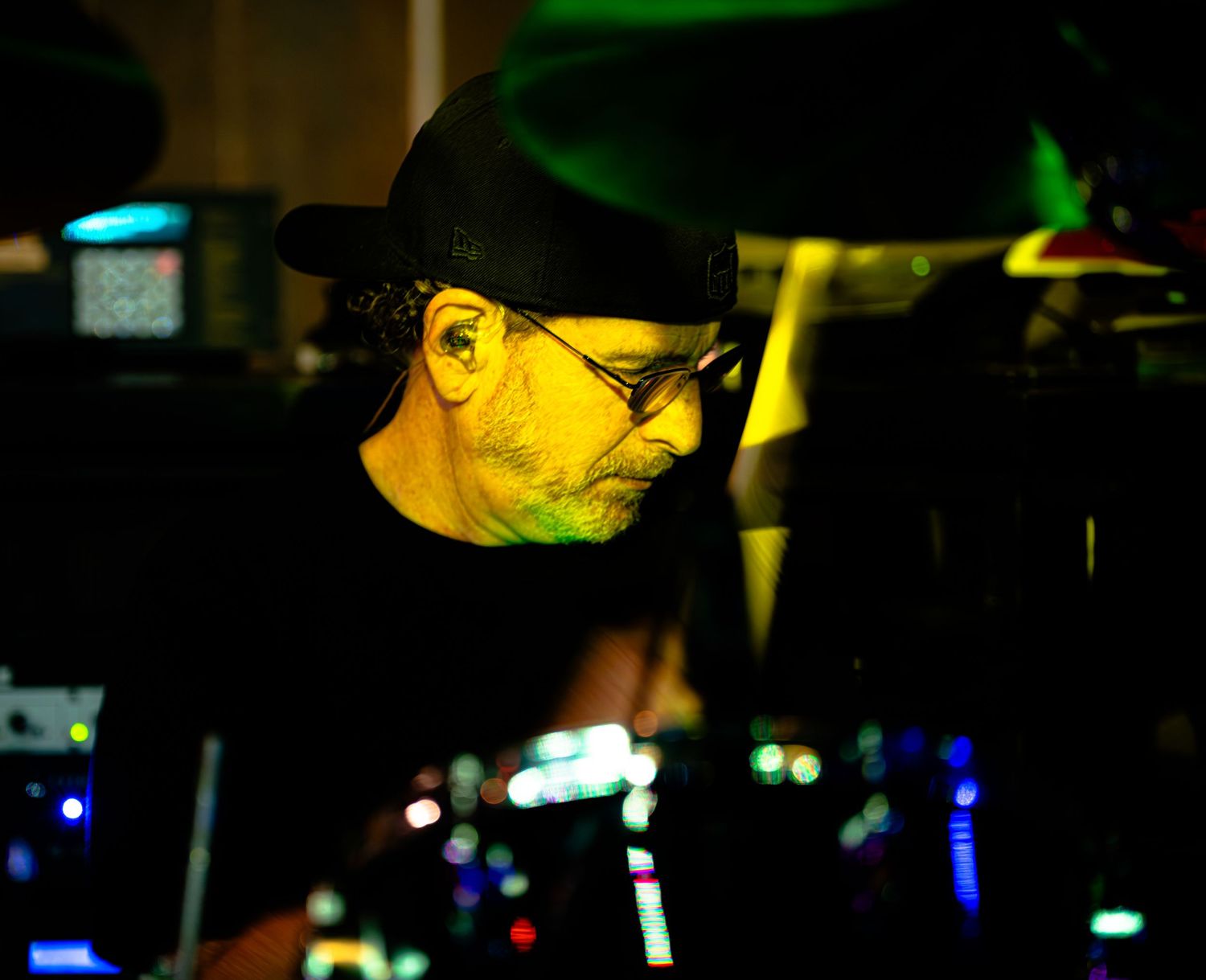 Performer wearing a cap illuminated by yellow stage lighting during a live show.