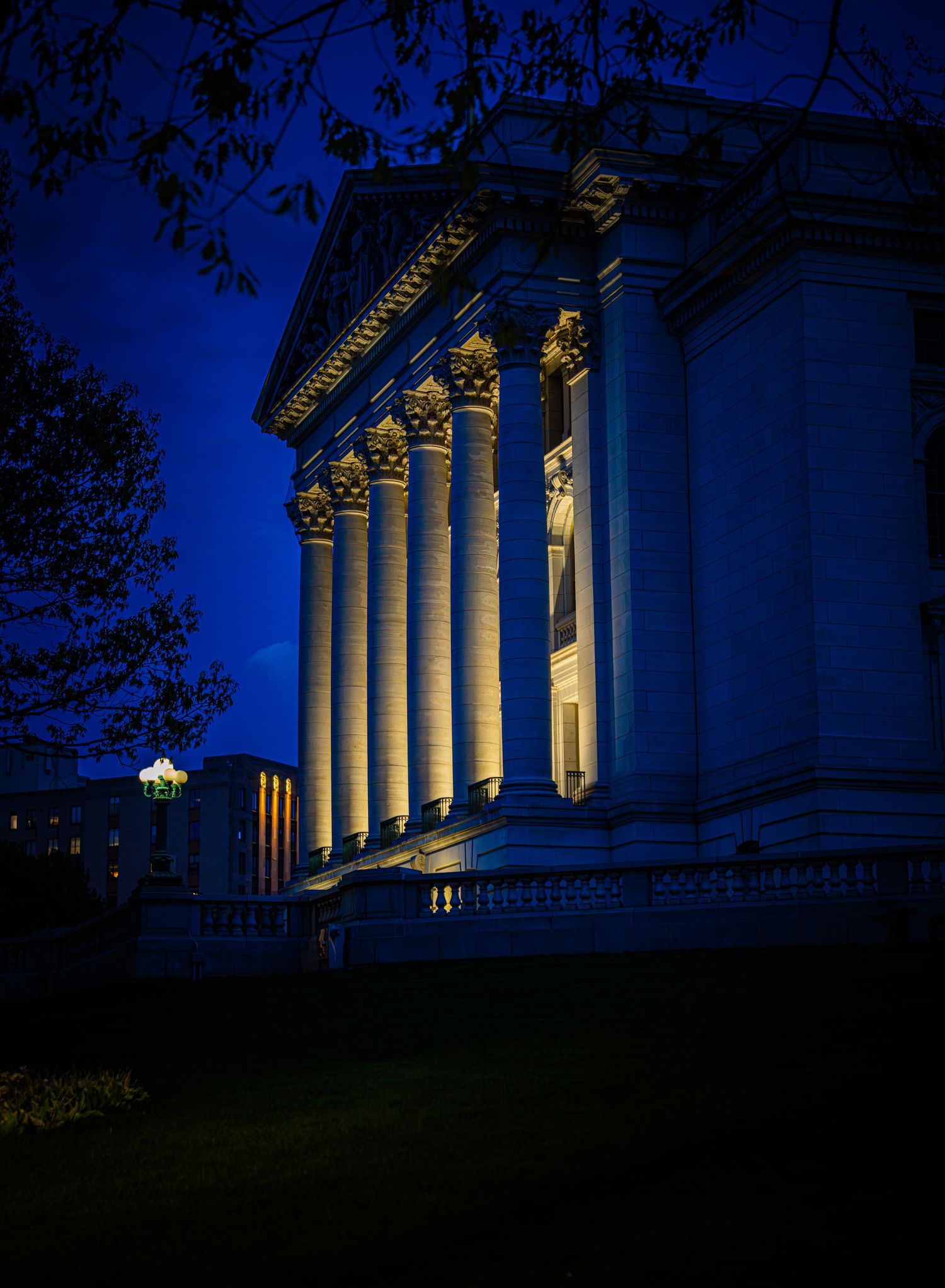 Illuminated neoclassical building with Corinthian columns glowing against a deep blue night sky.