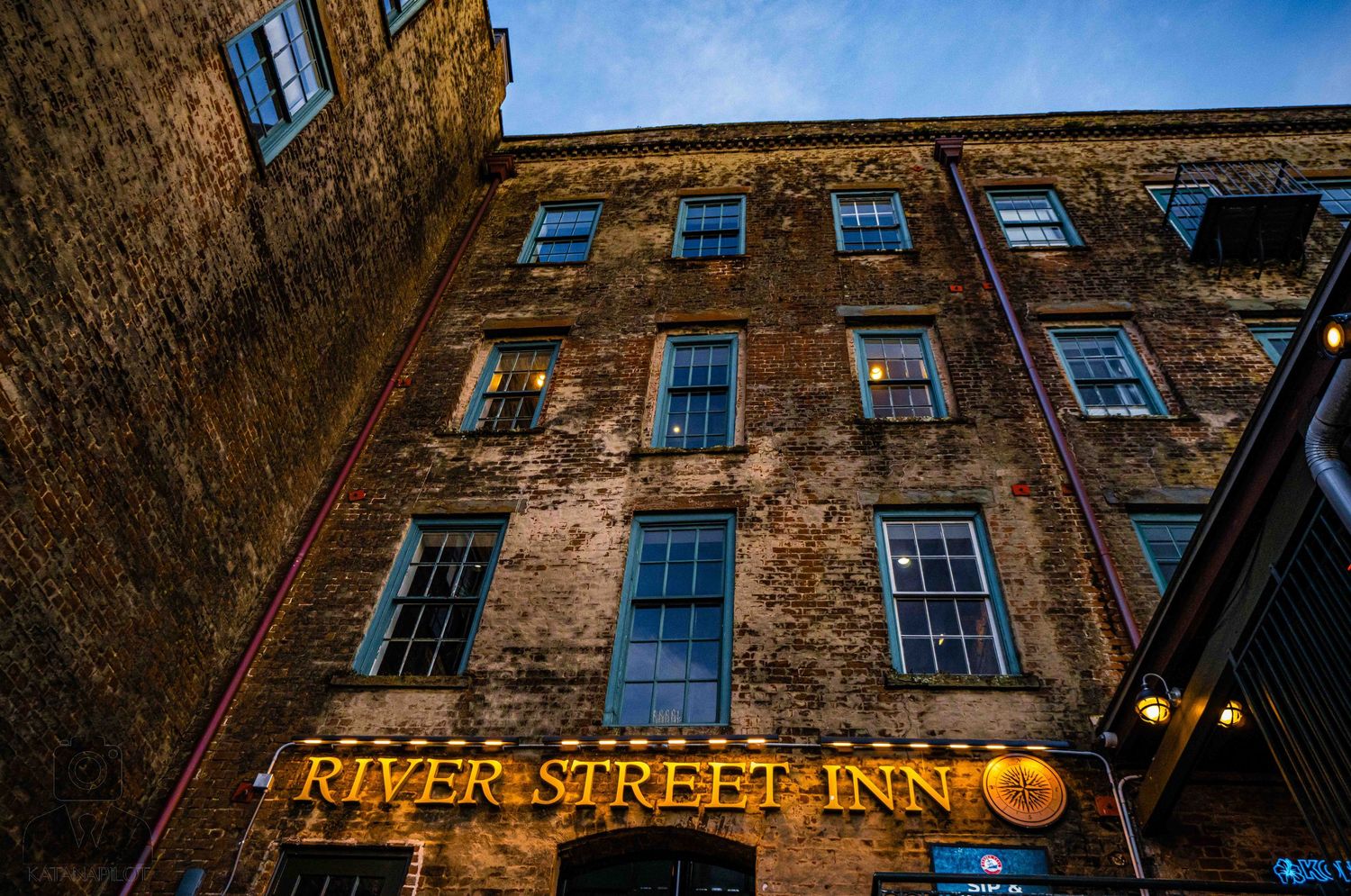 Historic brick buildings with windows line a street under blue sky in an urban setting.