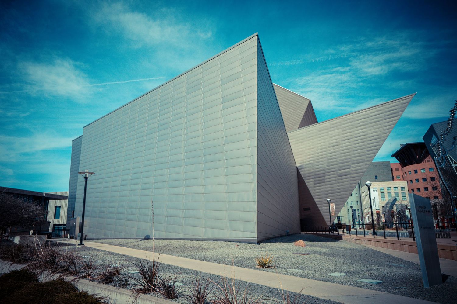 Panoramic sequence of modern angular white building facade against bright blue sky.