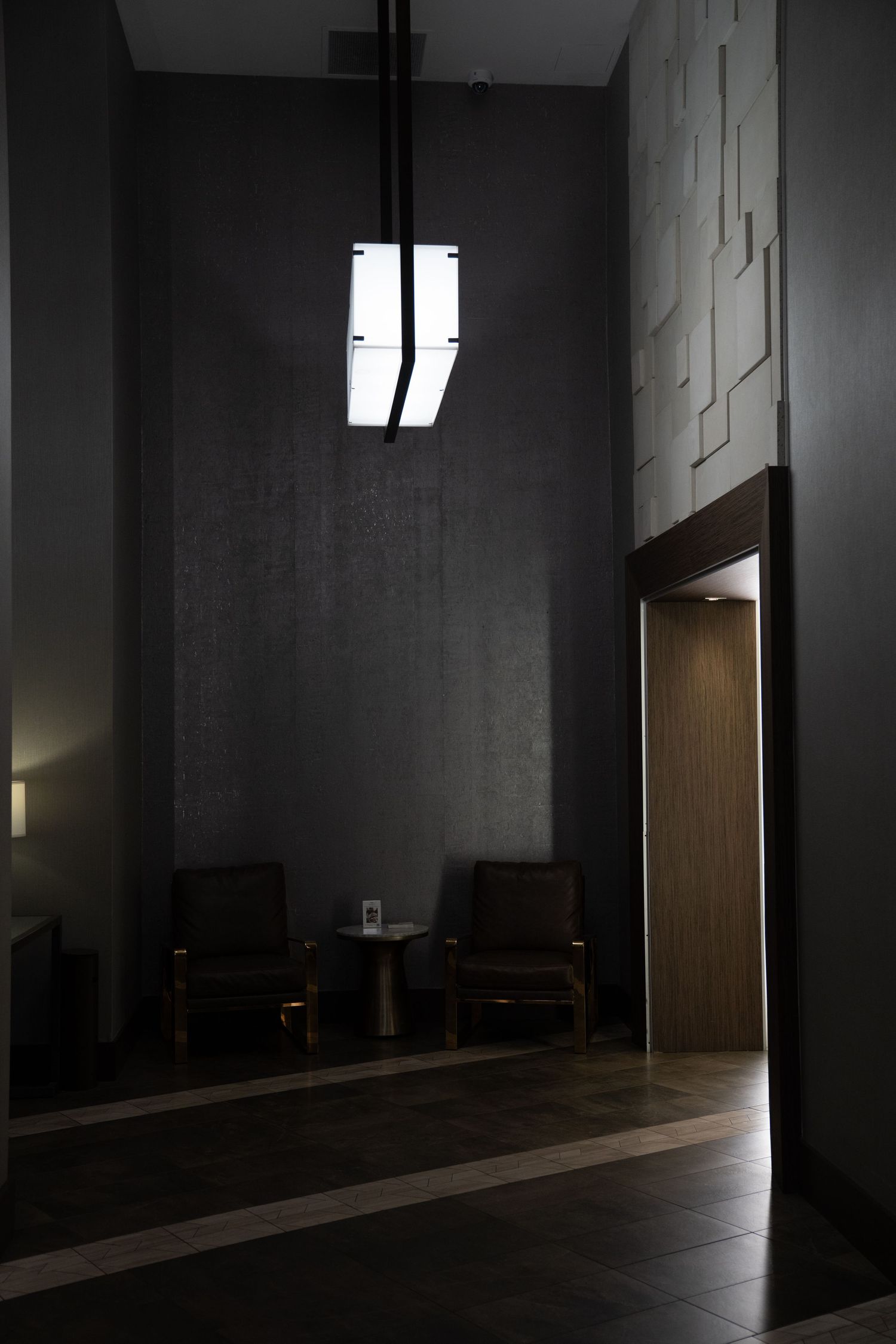 Minimalist concrete hallway with dramatic shadows and ambient lighting.
