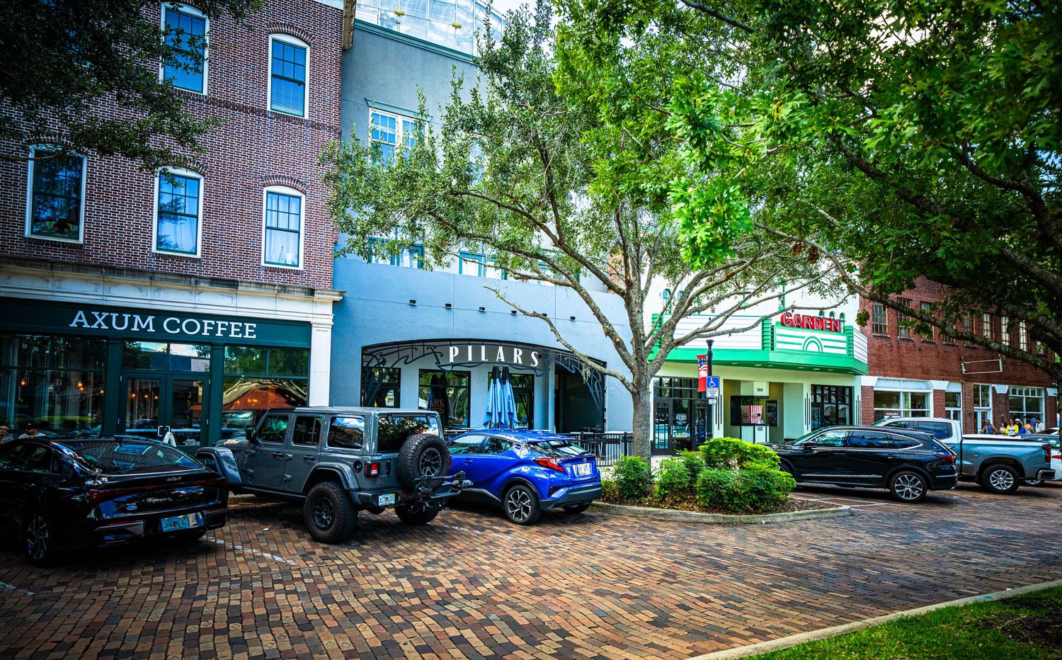 Commercial strip mall exterior with brick facade and parked vehicles along storefront.