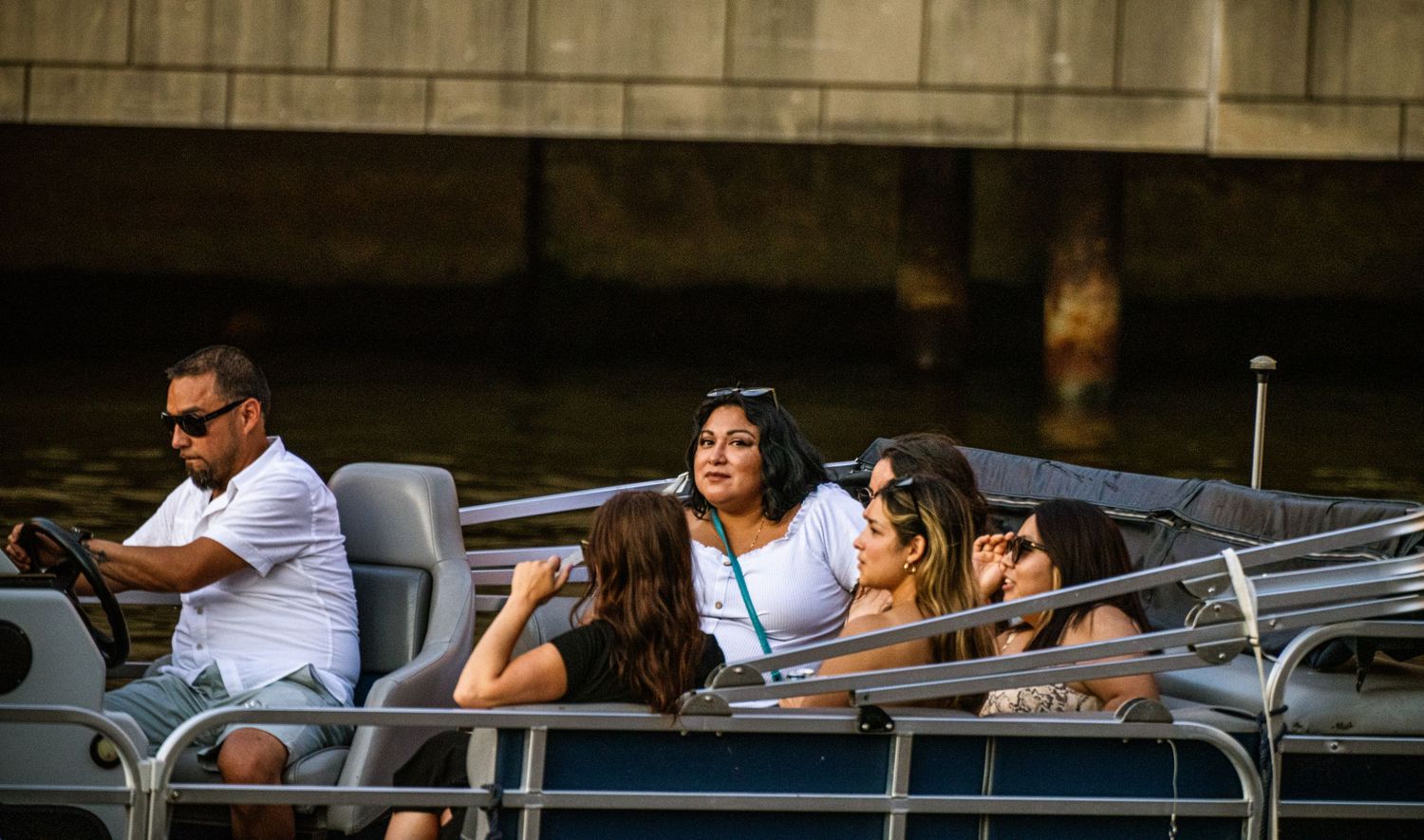 People enjoying a summer day on rental boats at a city waterfront with golden sunlight reflecting on the water.