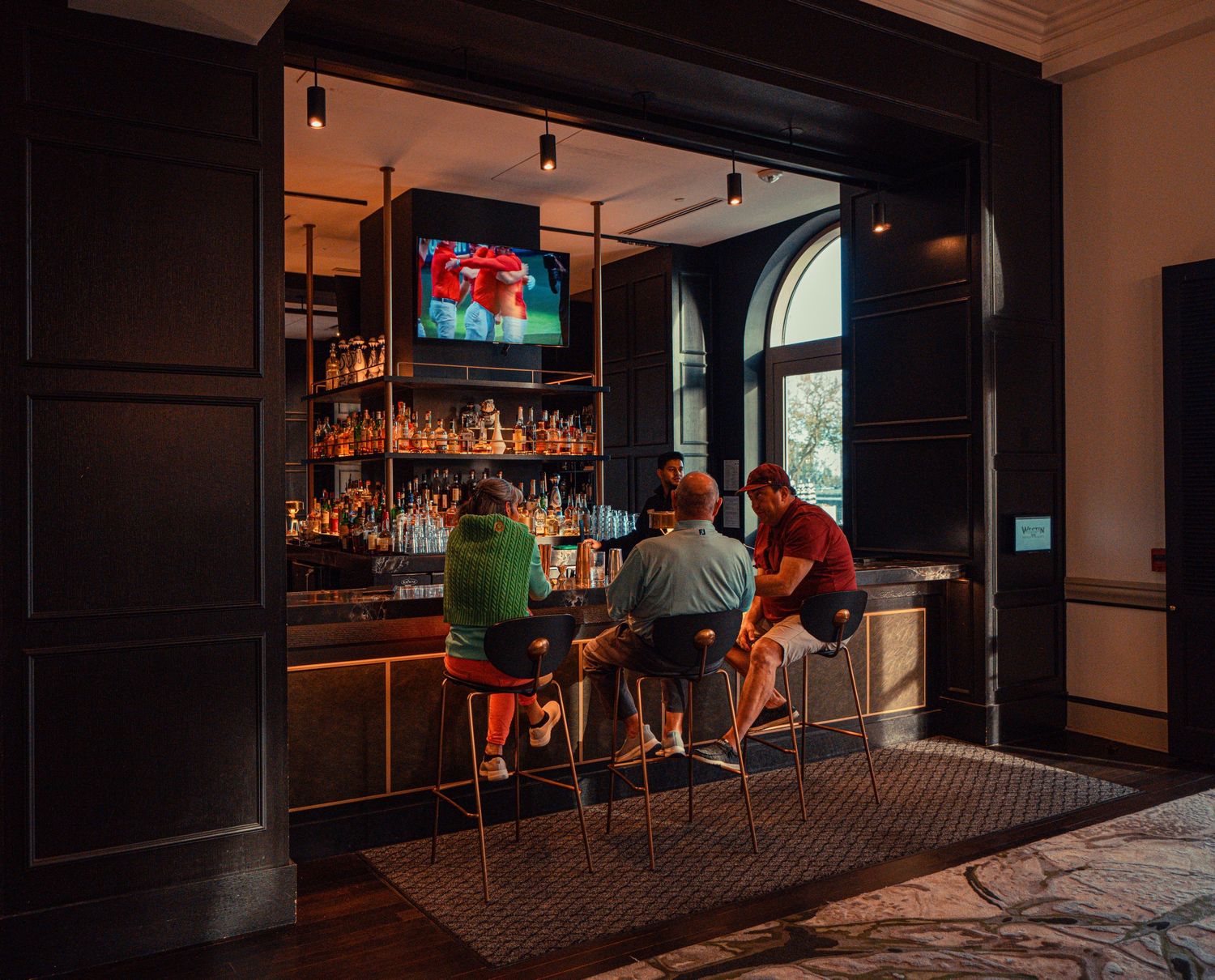 Dark interior view of a modern bar with ambient lighting and seating along the counter.