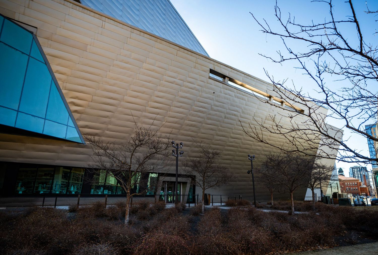 Modern architectural exterior with curved metal panels and glass windows stretches across multiple connected buildings.