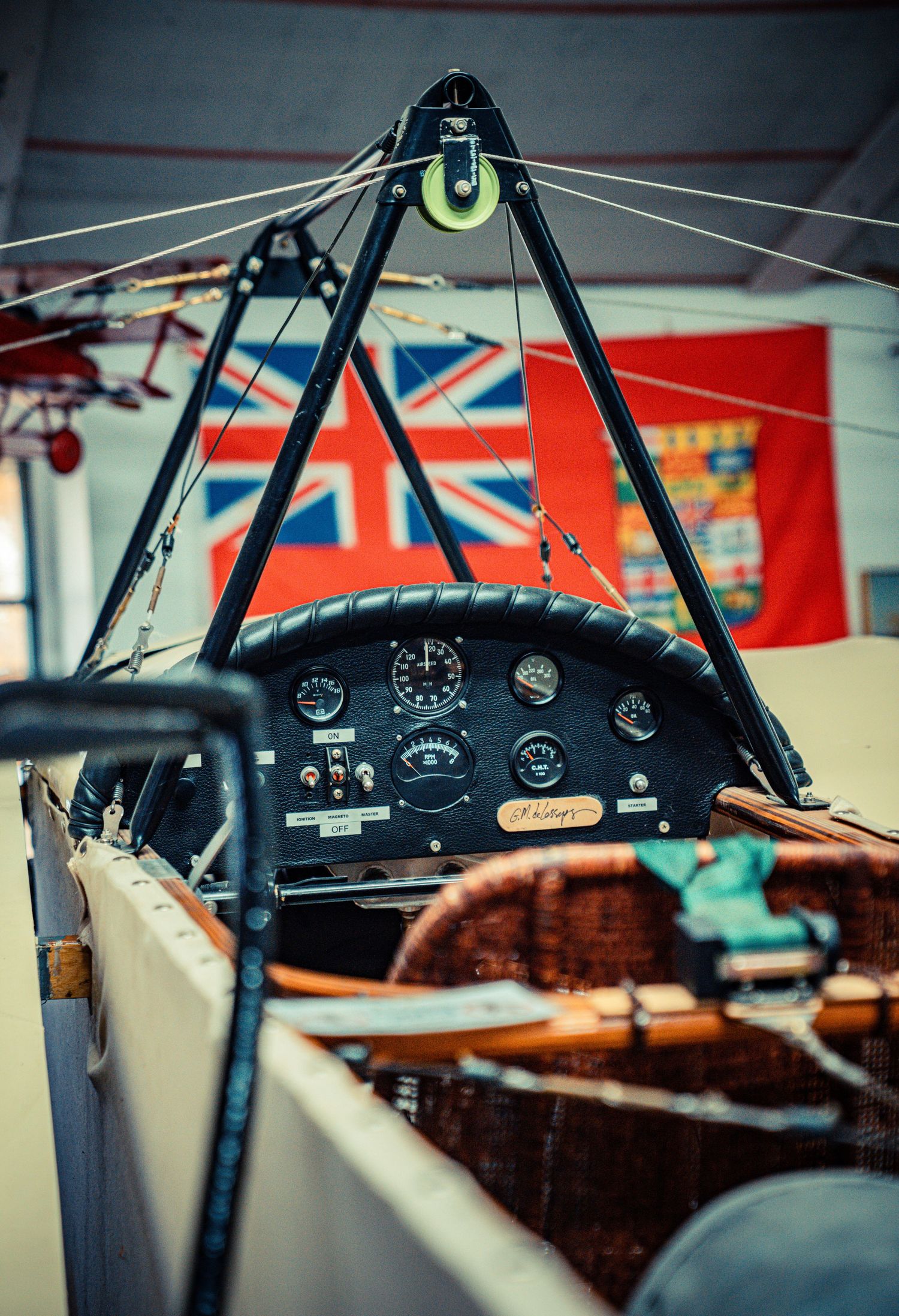 Vintage aircraft cockpit dashboard with instruments against Union Jack flag background.