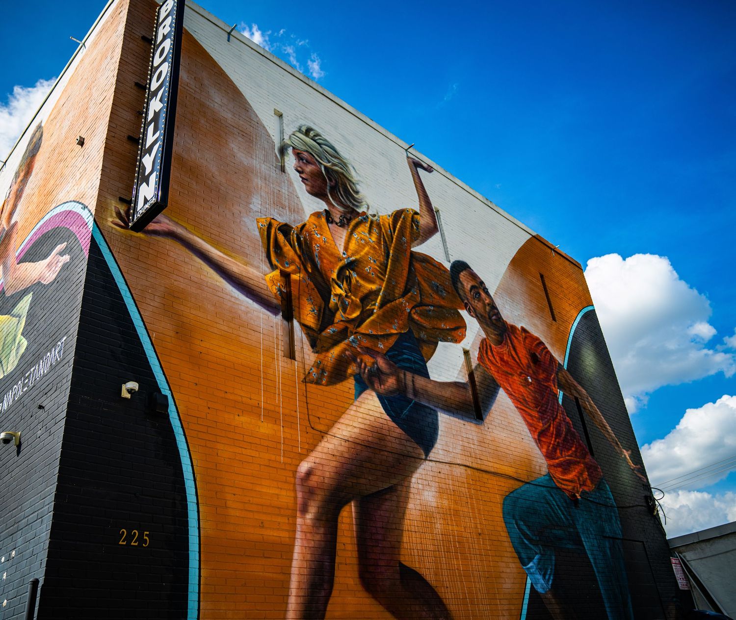 Panoramic view of colorful outdoor murals depicting sports figures on building walls.