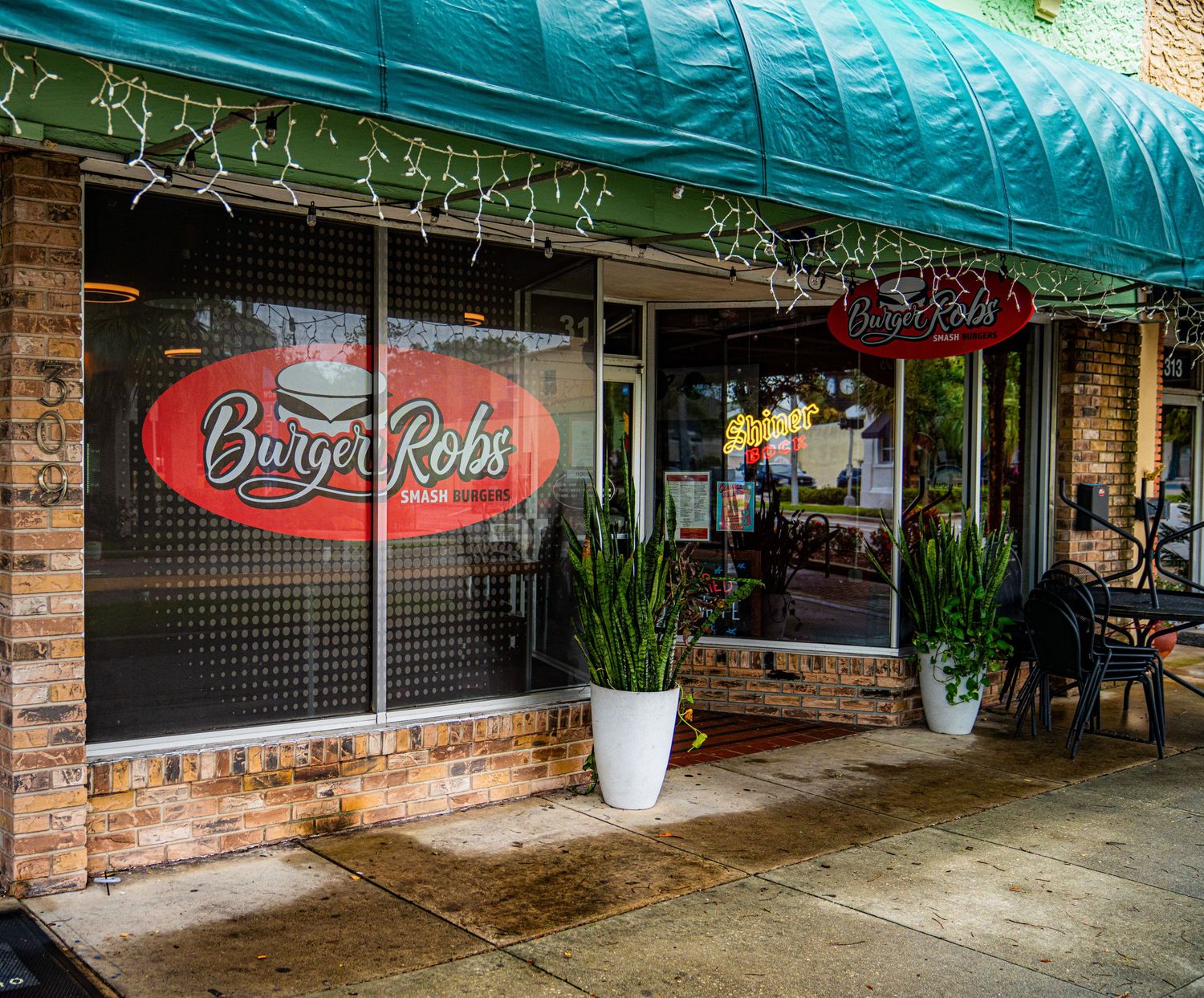 Shopping center exterior with turquoise awning and exposed brick facade.
