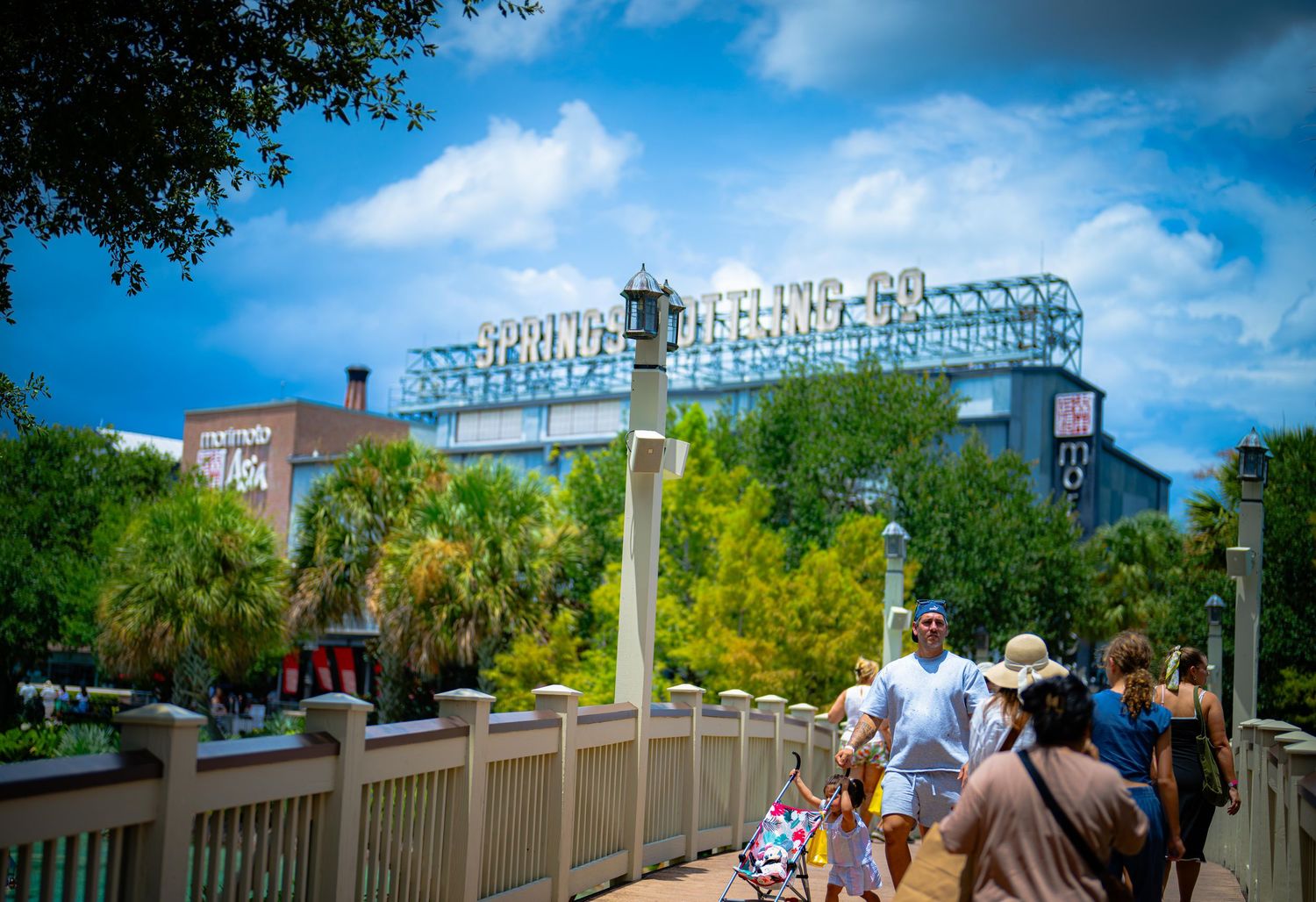 Visitors walk toward the Spring Trading Co. sign at Disney Springs, Florida, under a vibrant blue sky.