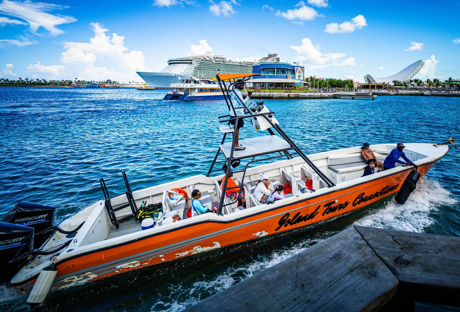 Orange Island Time Cruises boat docked in Miami harbor with a large cruise ship in the background.