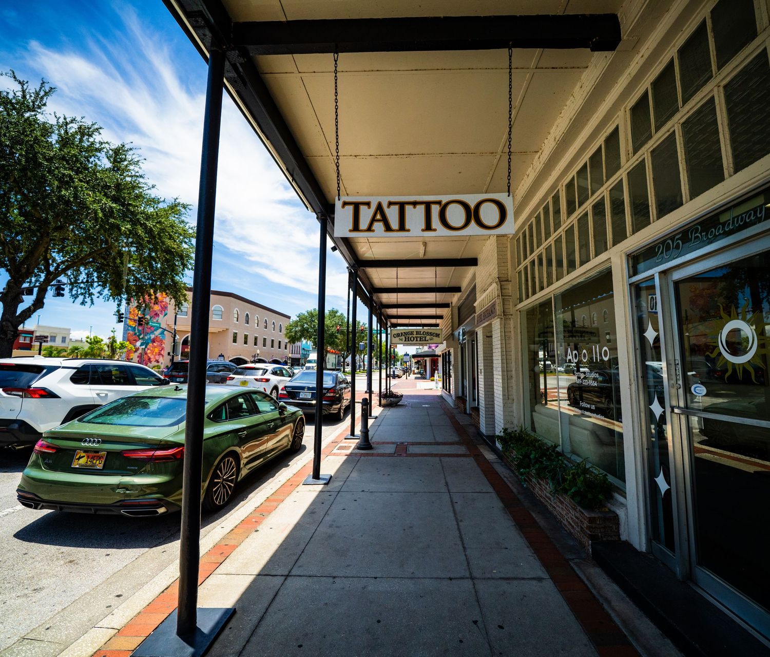 Long covered walkway with retail storefronts and brick columns in shopping center.