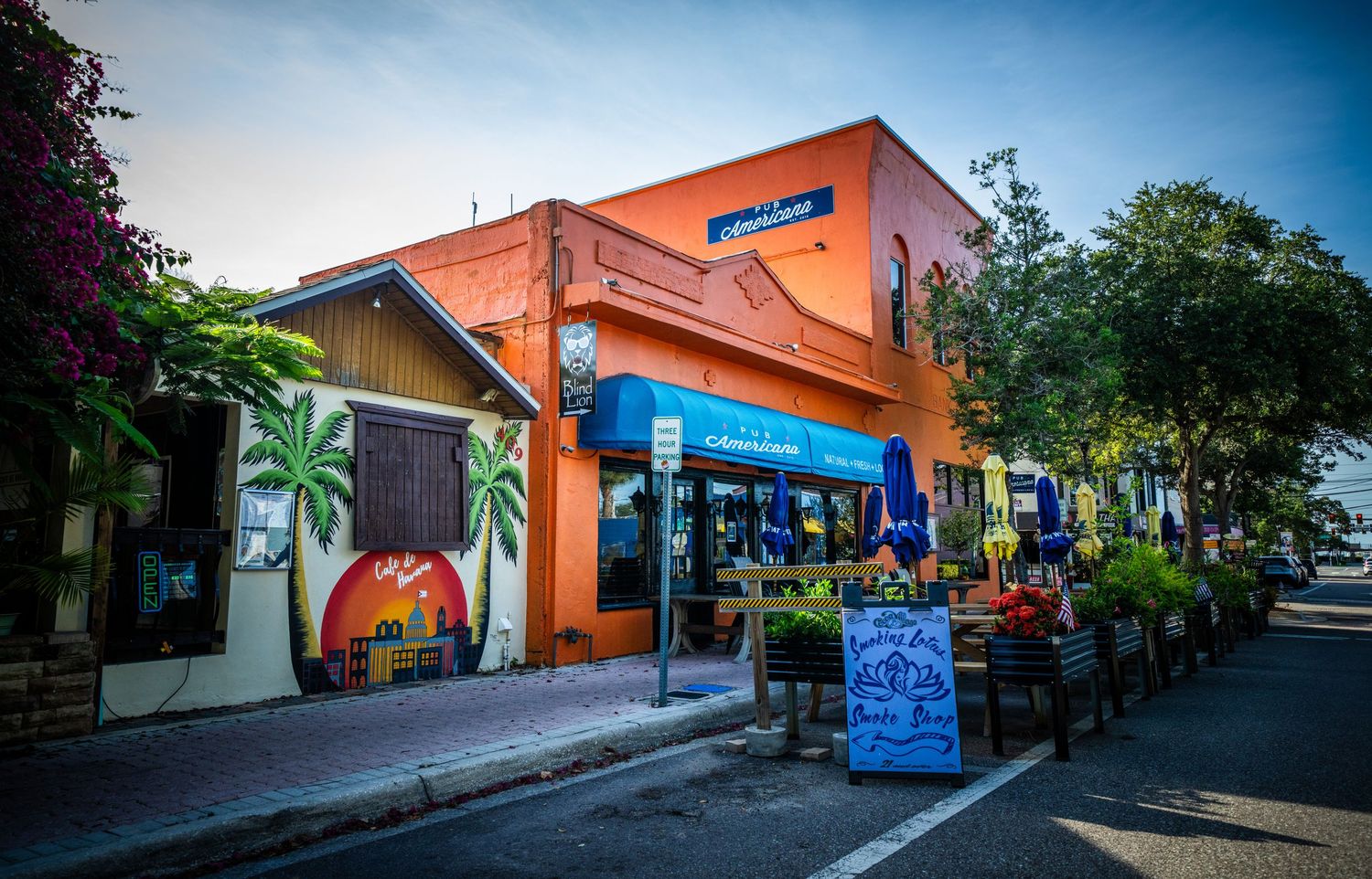 Colorful beach-themed retail shops with outdoor seating and palm tree murals.