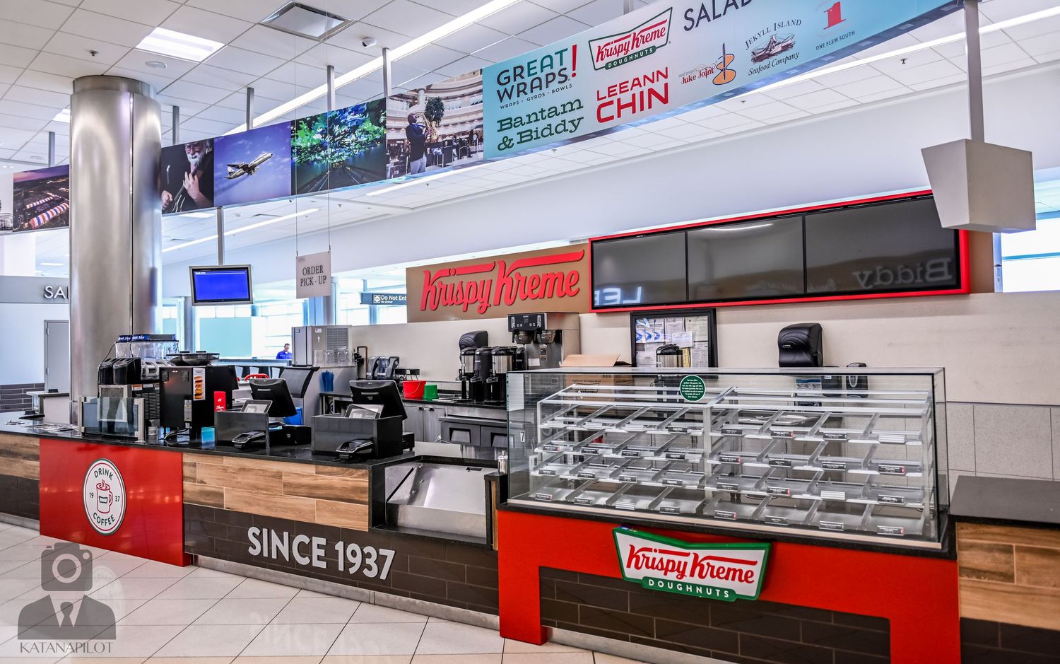 Long retail counter with display cases and branded signage in a bright commercial space.