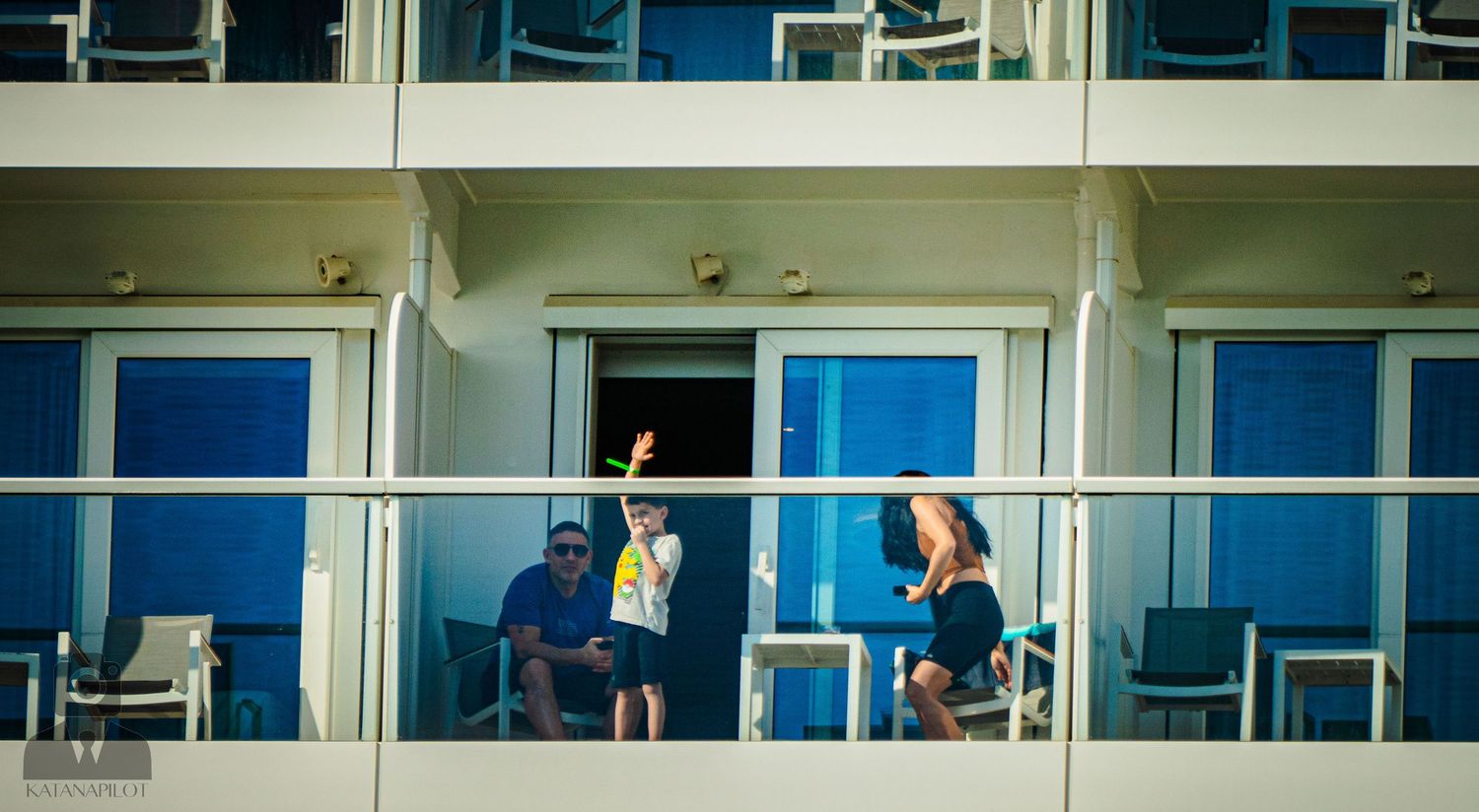 Spectators watch from multiple balconies of a modern building with blue sky in the background.