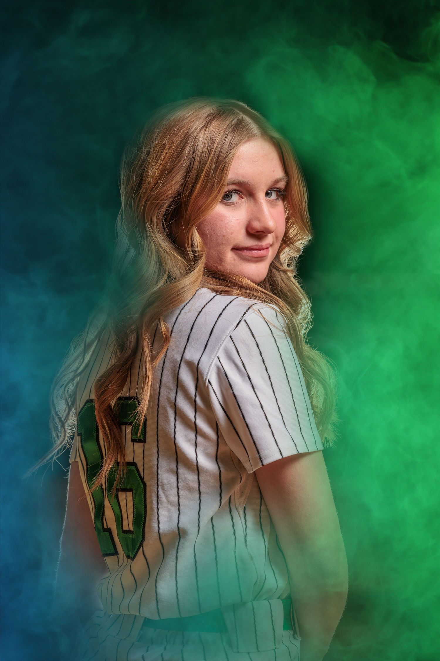 Person in pinstriped baseball jersey poses against atmospheric blue and green smoke effect background.