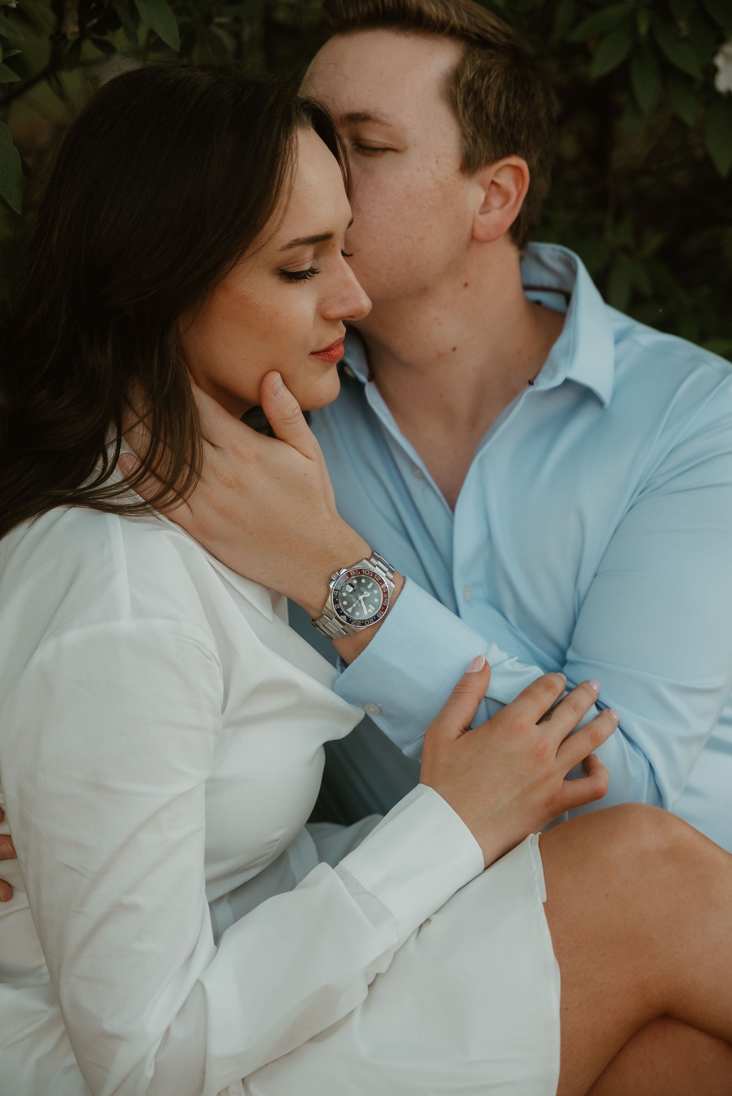 Couple sharing an intimate moment with man kissing woman on cheek outdoors.
