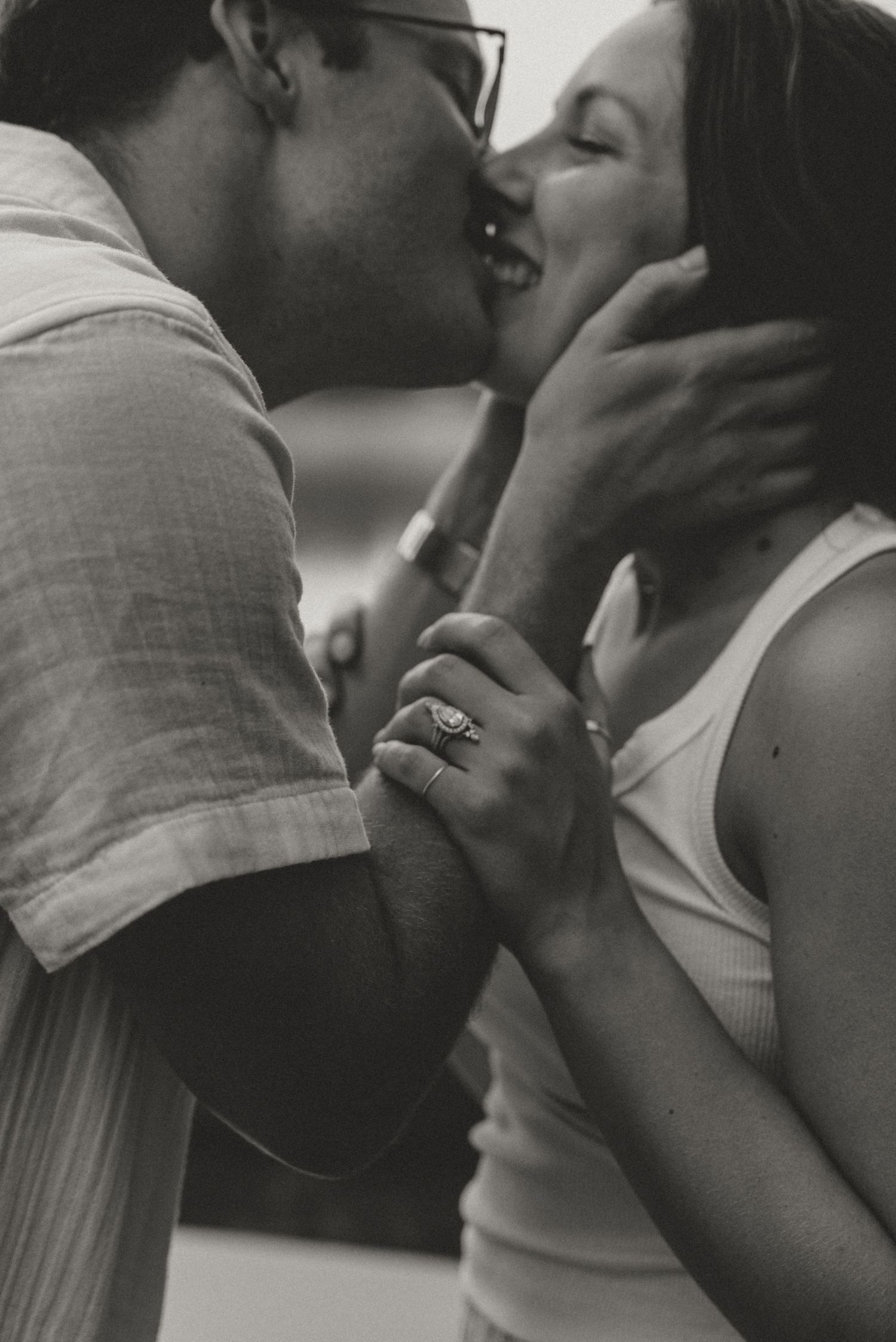 Black and white photo of engaged couple sharing a joyful kiss during romantic engagement session.