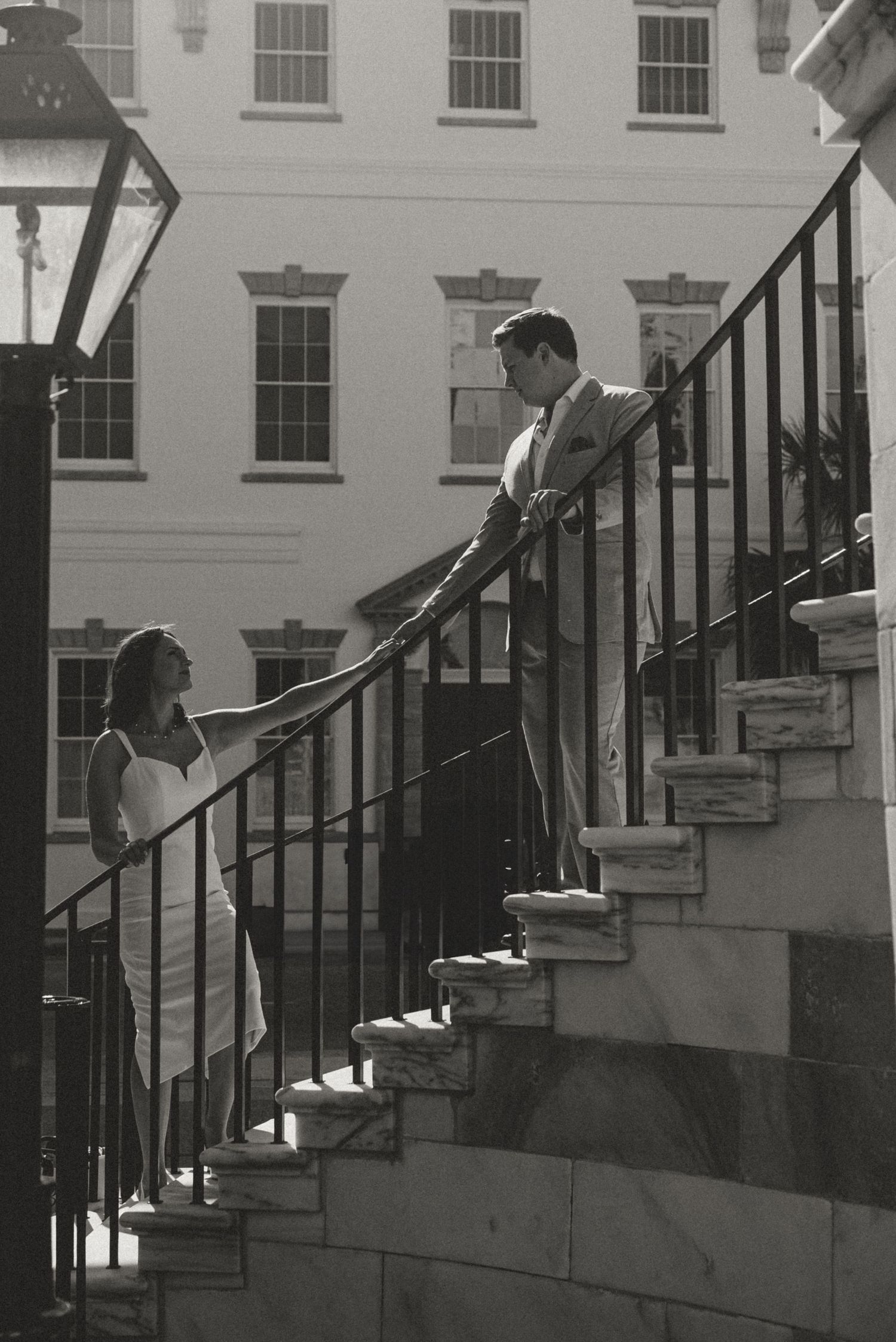 Black and white photo of couple sharing a moment on ornate outdoor staircase.