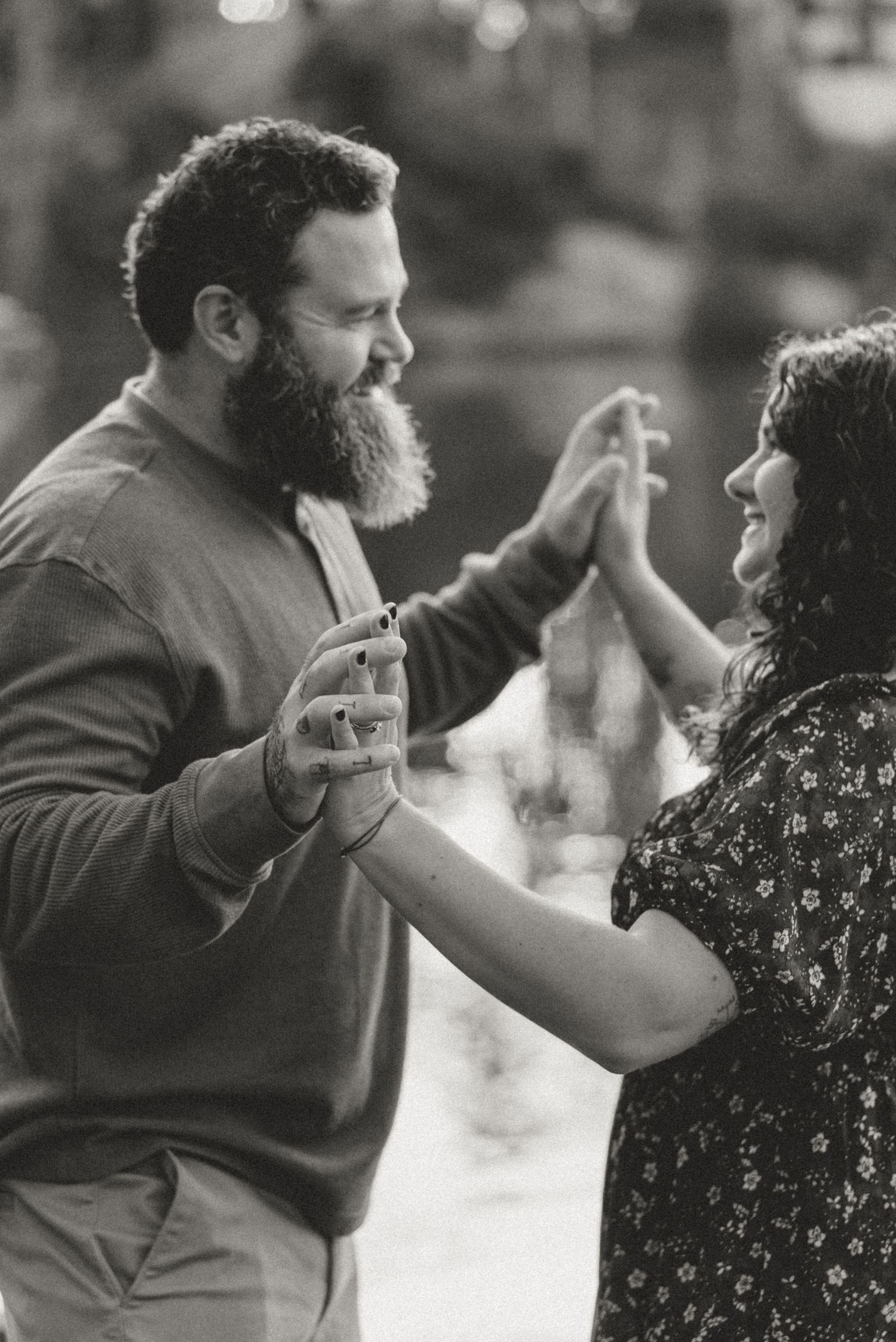 Black and white photo of a bearded man and woman dancing together outdoors.