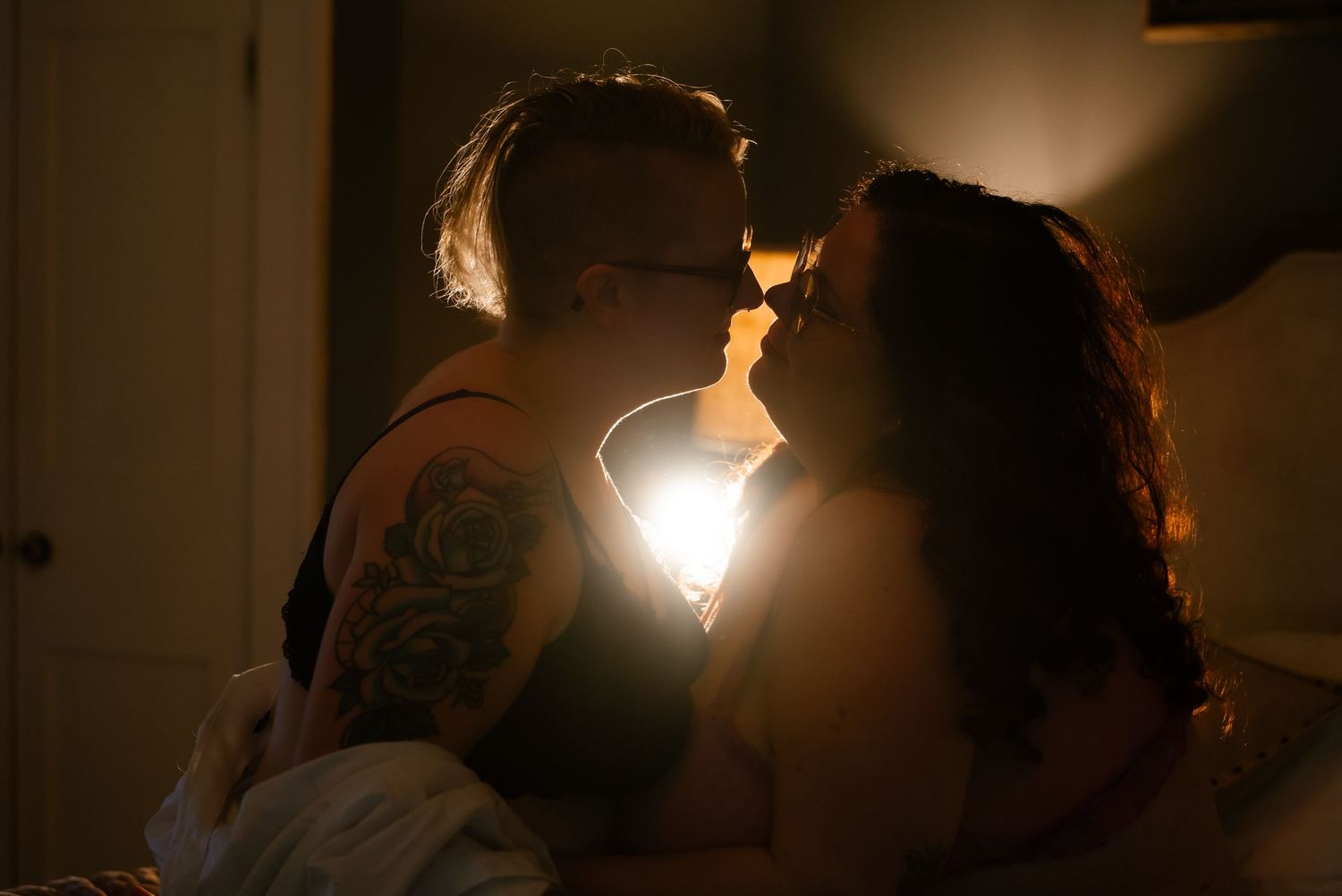Romantic couple sharing an intimate kiss in a warmly lit bedroom at night.