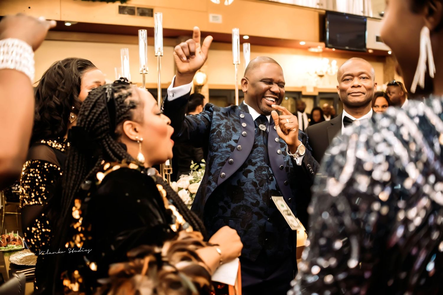 A joyful celebration scene at what appears to be a reception or party with people dancing and laughing together.