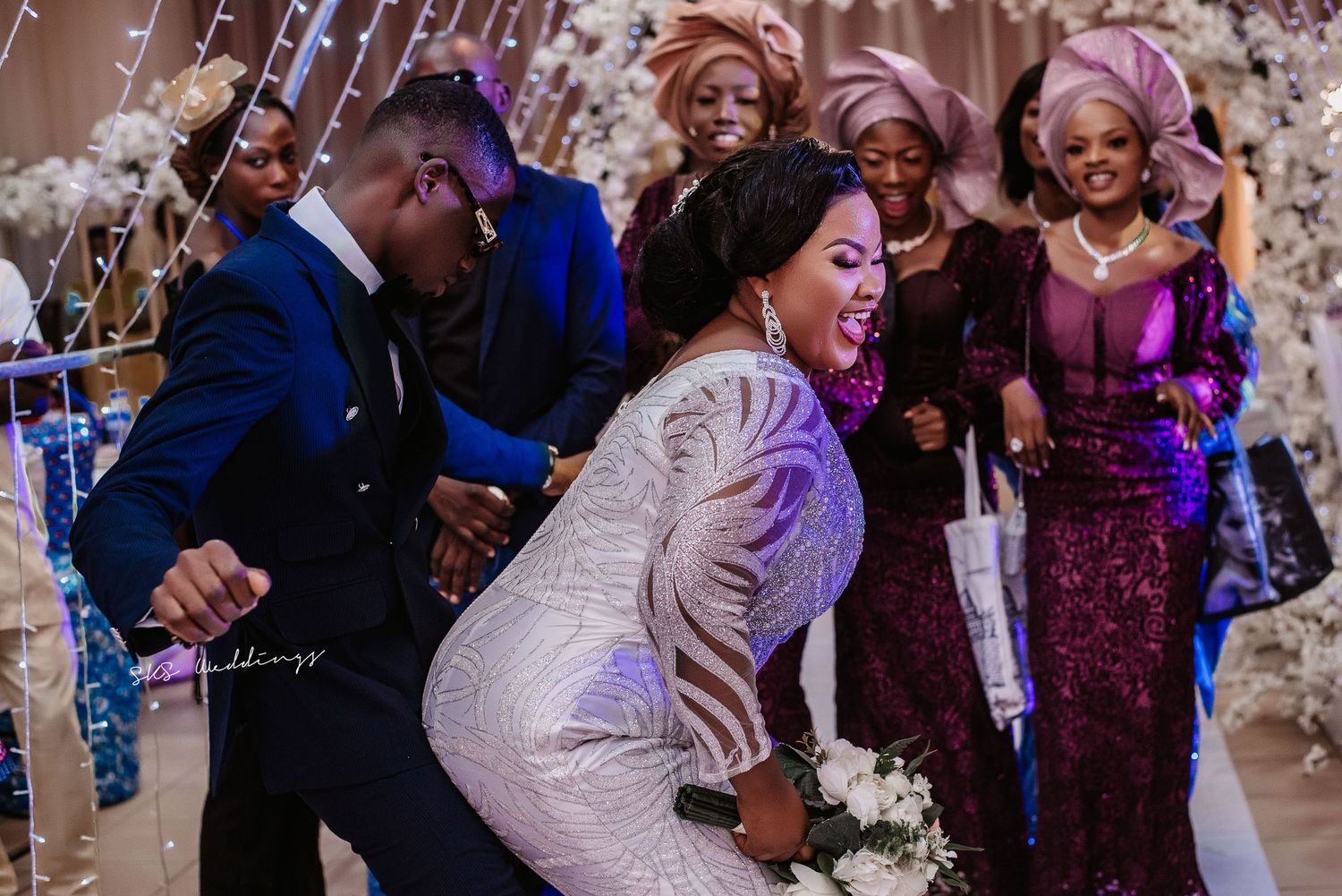 Wedding celebration with dance moves on the reception floor as guests cheer and confetti falls from above.