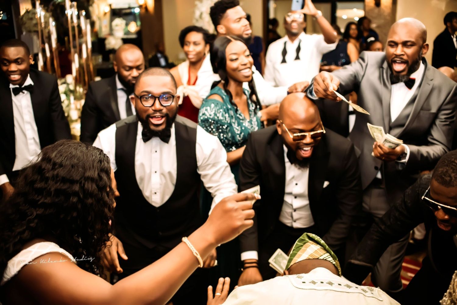 A joyous celebration at an elegant formal event with partygoers in tuxedos and formal attire sharing laughs together.