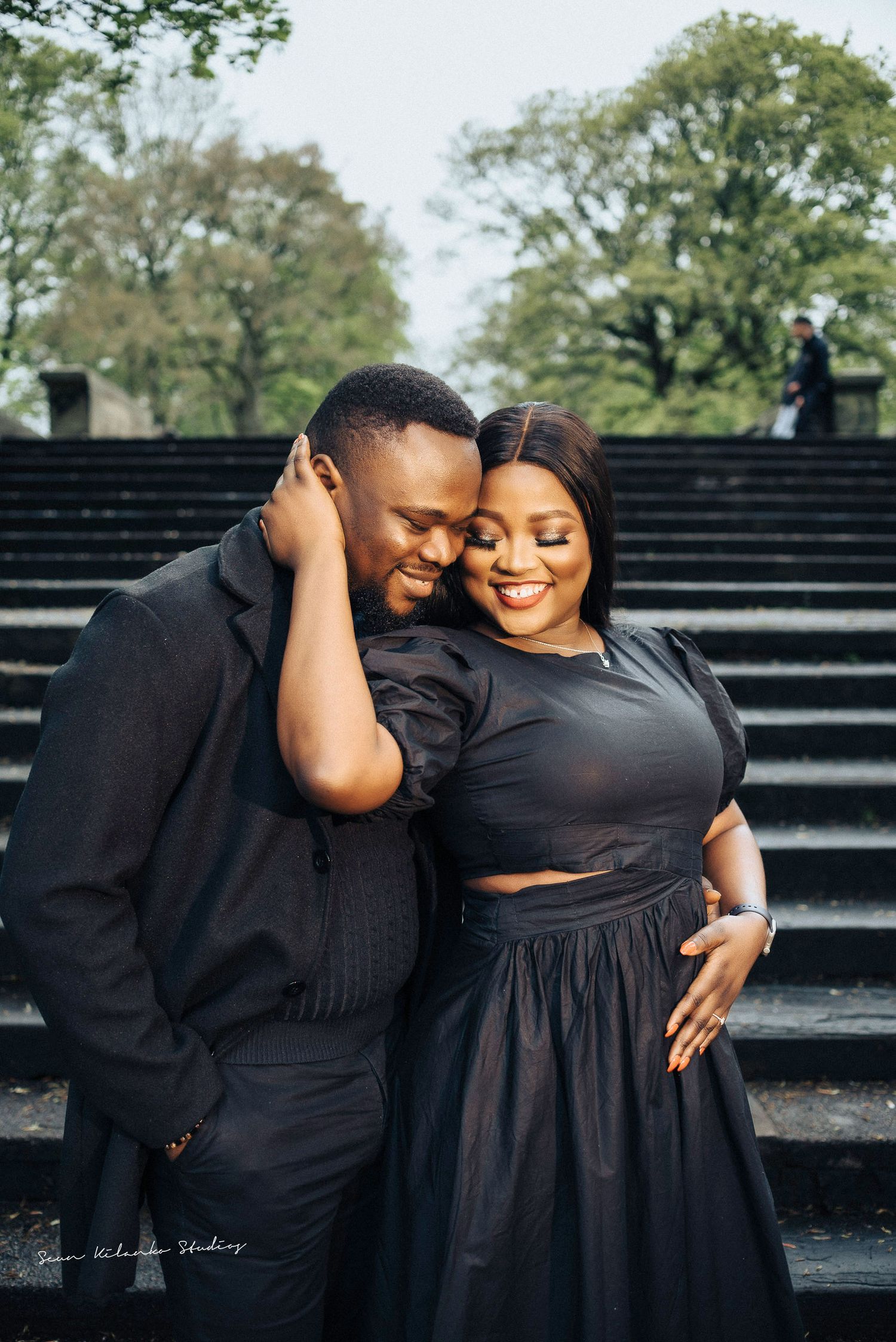 Joyful couple shares a laugh while embracing on stone steps during their photoshoot.