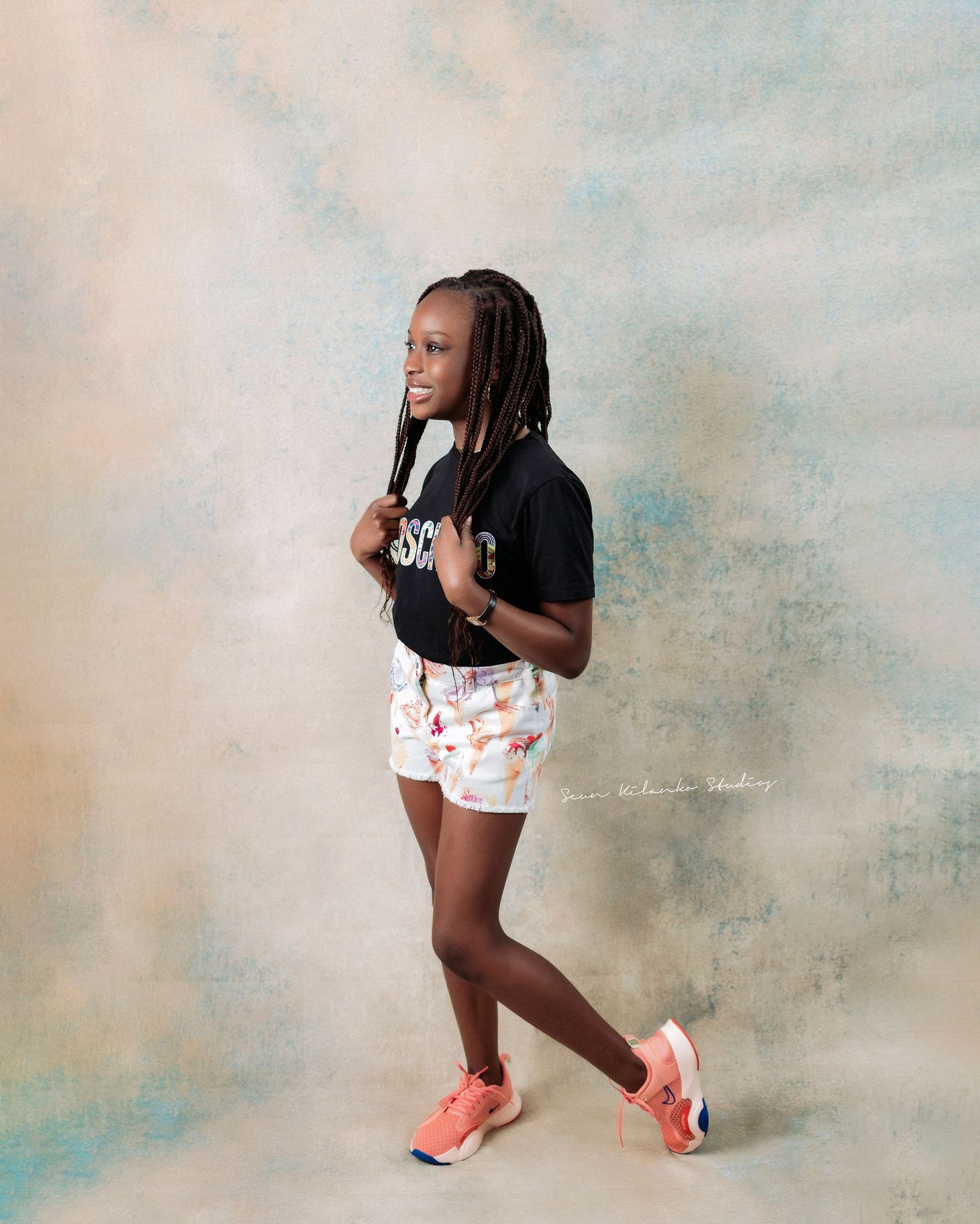 Casual portrait in black top and patterned shorts with coral sneakers.