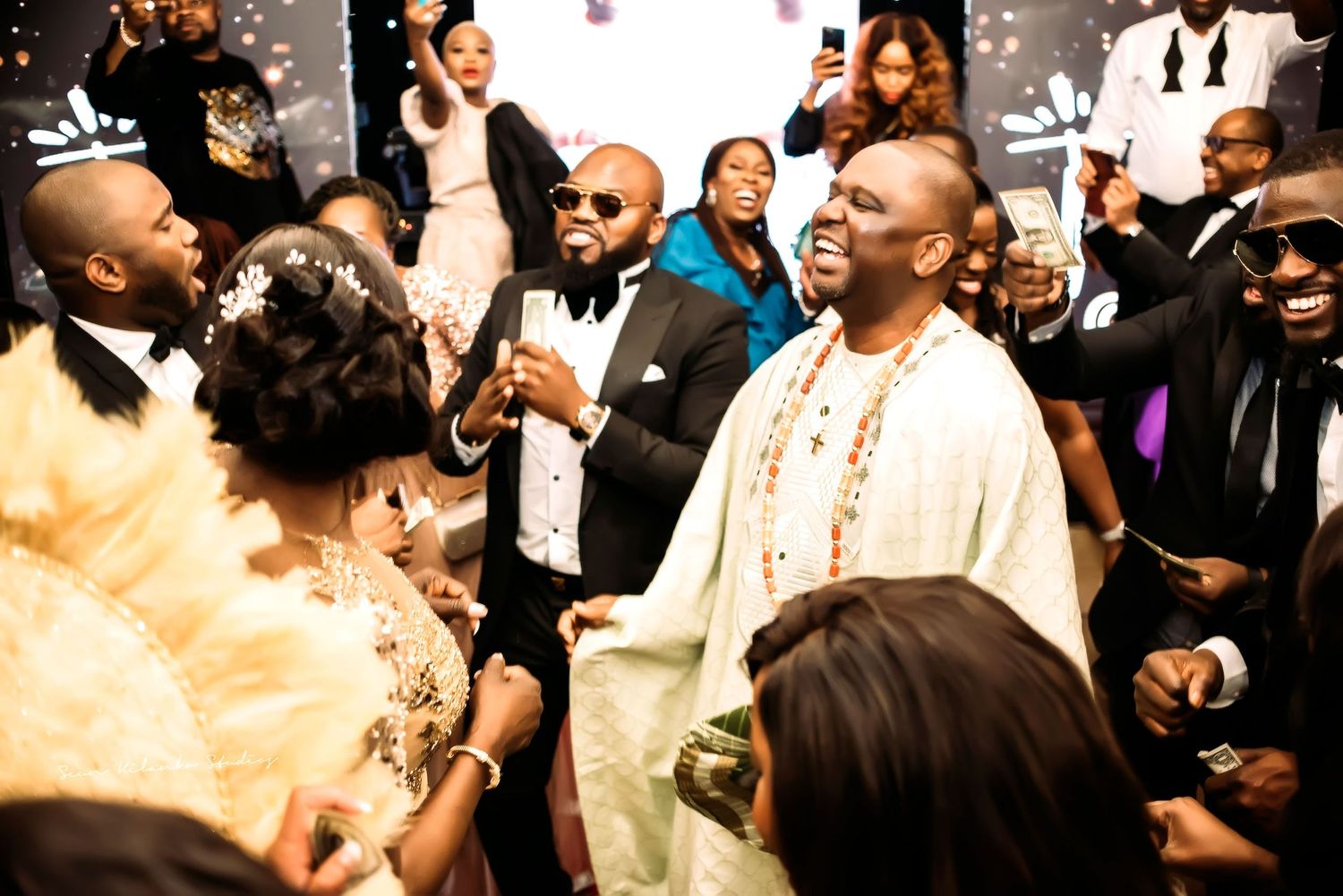A celebratory moment at an elegant wedding reception showing guests laughing and enjoying themselves in formal attire.