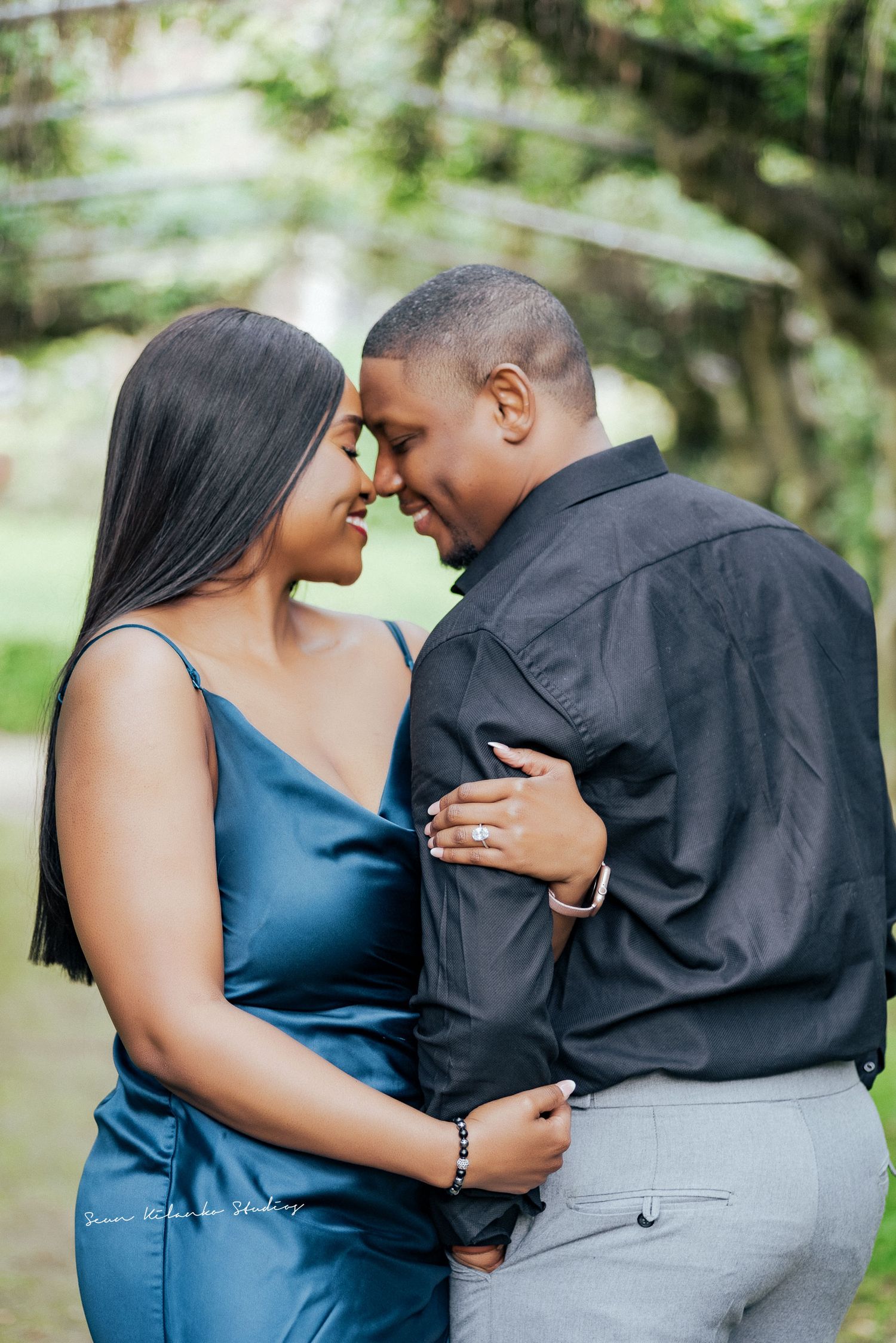 Intimate outdoor engagement photo with couple in blue dress and black shirt.