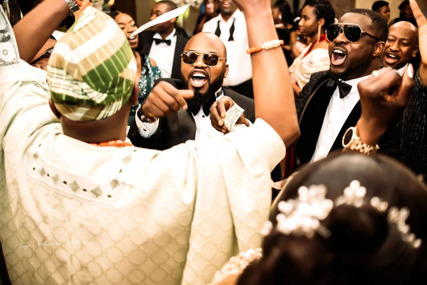 Joyful wedding celebration with guests dancing and singing together in festive formal wear.