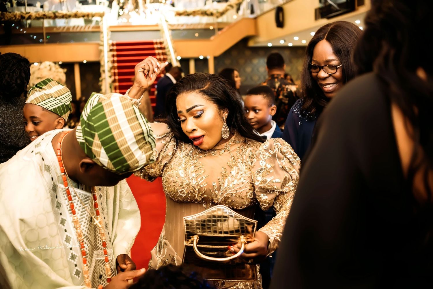 Guests celebrate and dance at a vibrant wedding reception with traditional attire and joyful atmosphere.