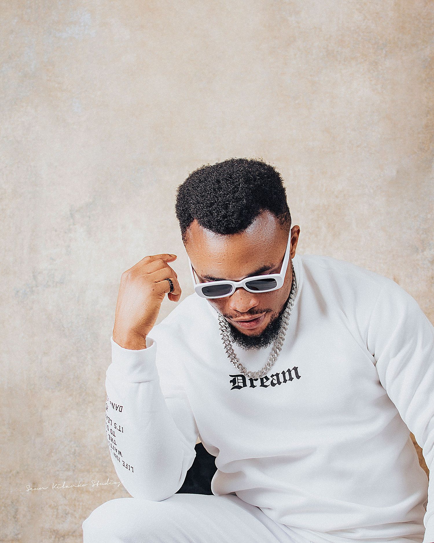 Person wearing white sweatshirt with 'Dream' text and sunglasses poses against beige background in collage style photos.