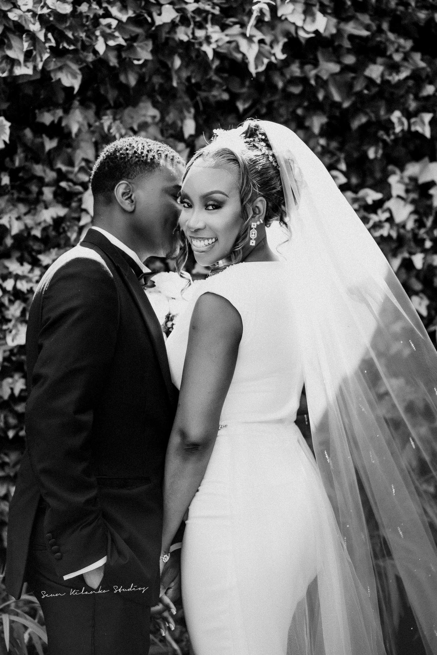 Black and white wedding portrait showing intimate moment against garden backdrop.