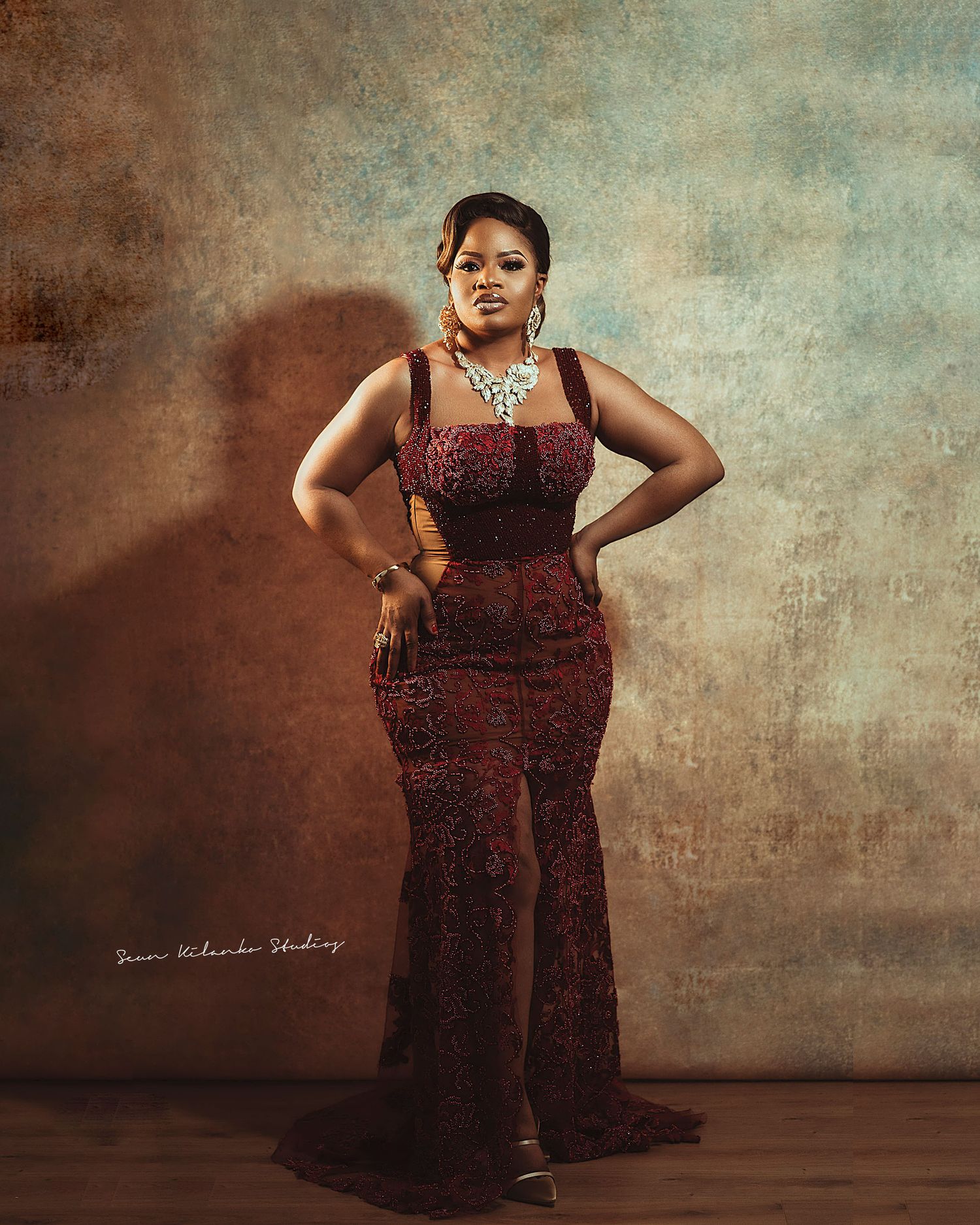 Elegant full-length pose in a fitted burgundy evening gown with dramatic mermaid silhouette.