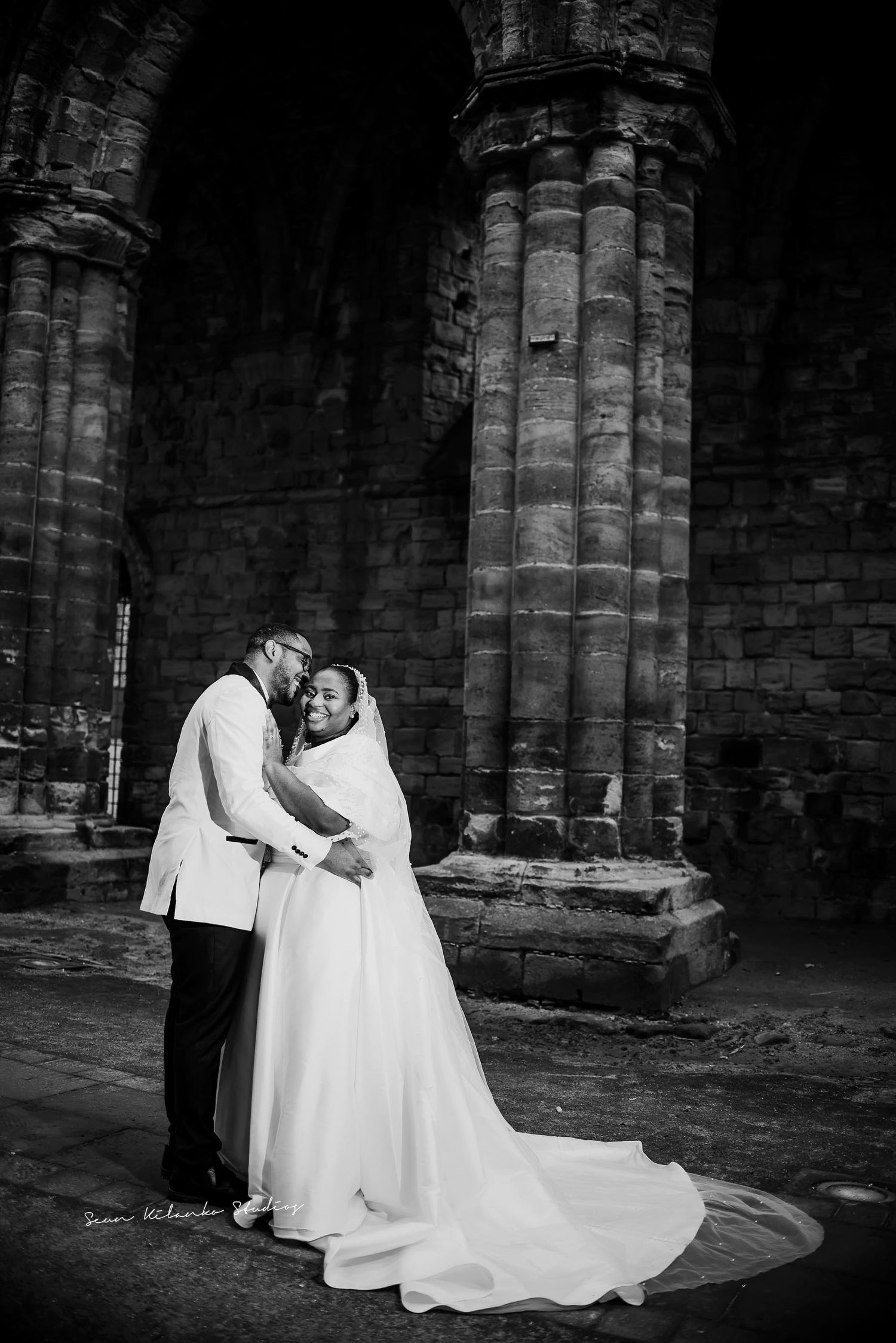 An intimate black and white wedding photo captured under dramatic cathedral columns.