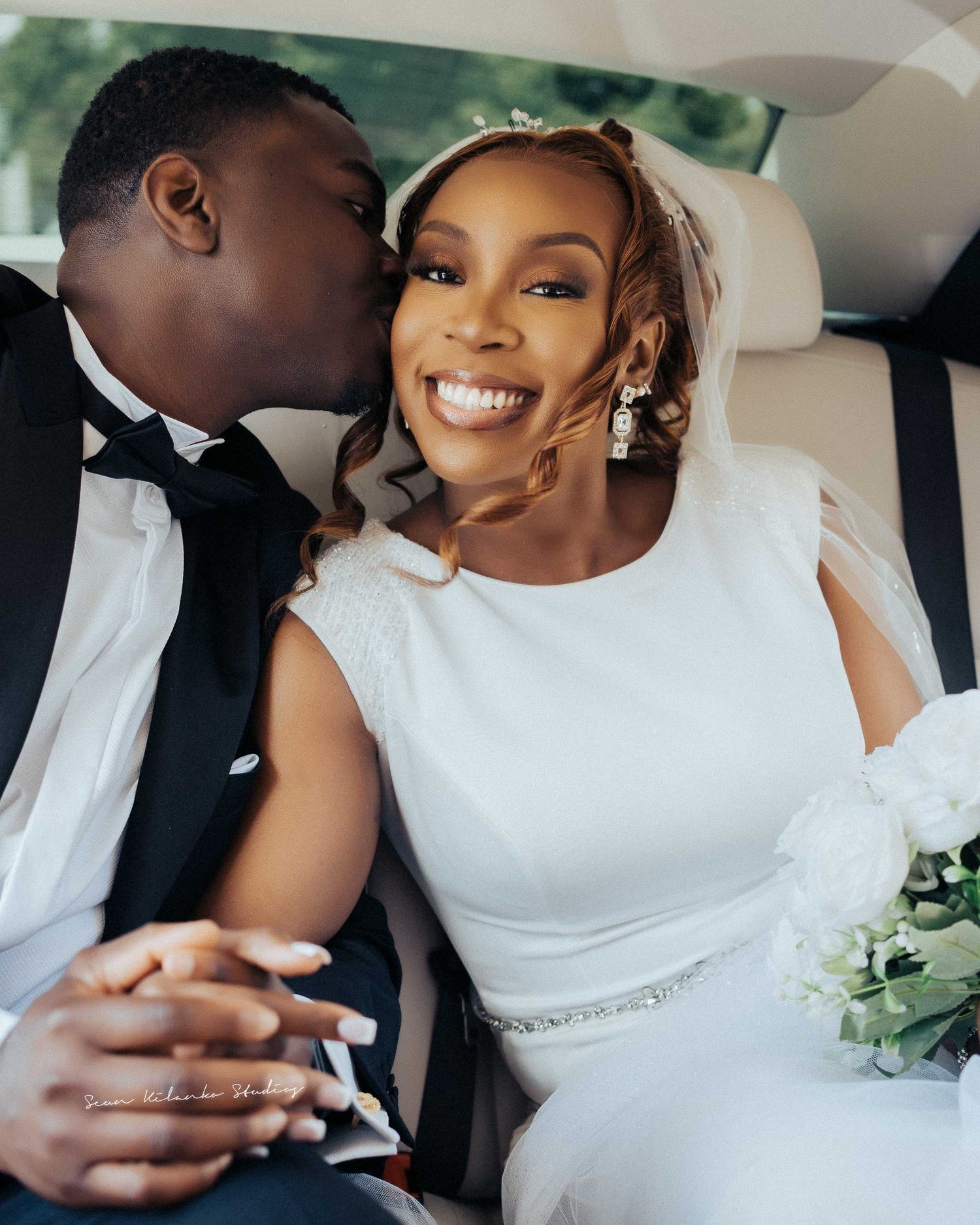 A joyful candid wedding moment captured in the back seat of a luxury vehicle.