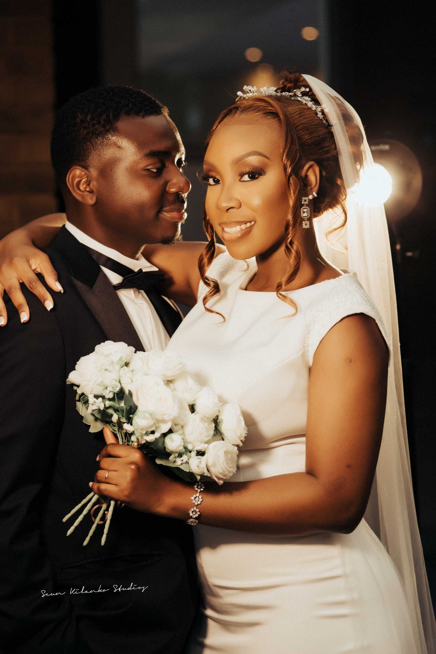 Intimate wedding portrait of a couple with white bouquet and formal attire.