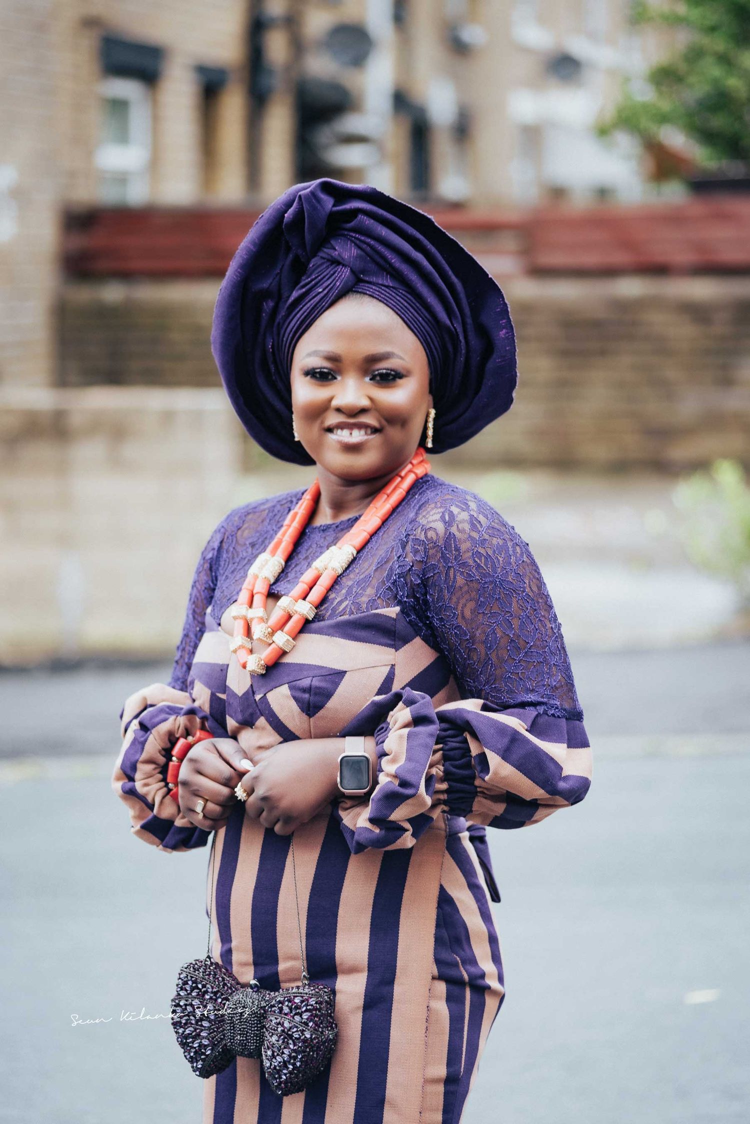 Traditional Nigerian fashion featuring purple gele headwrap and striped ankara fabric outfit.