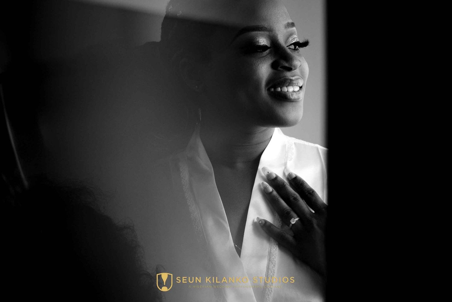 A joyful smile captured in an intimate black and white portrait photograph with dramatic side lighting.