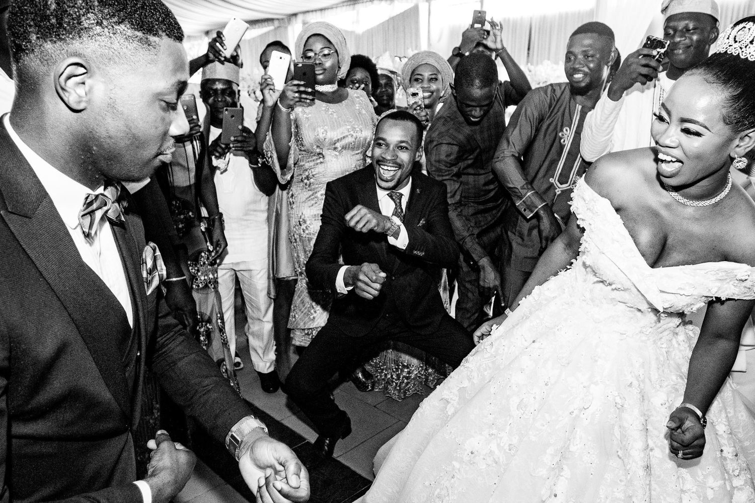 Black and white candid wedding photo showing joyful dancing and celebration at a reception.