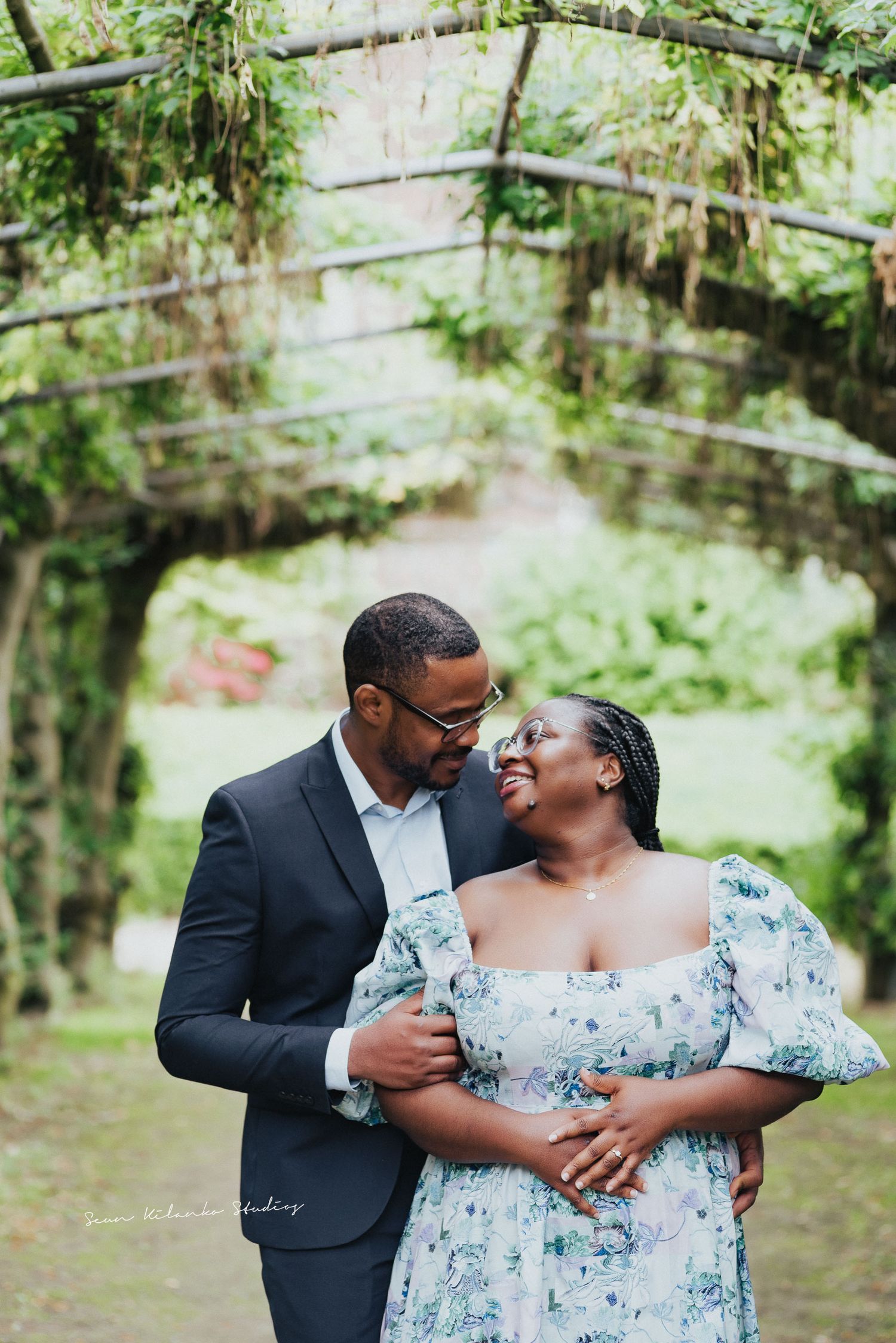 Intimate portrait of couple embracing under green garden archway.