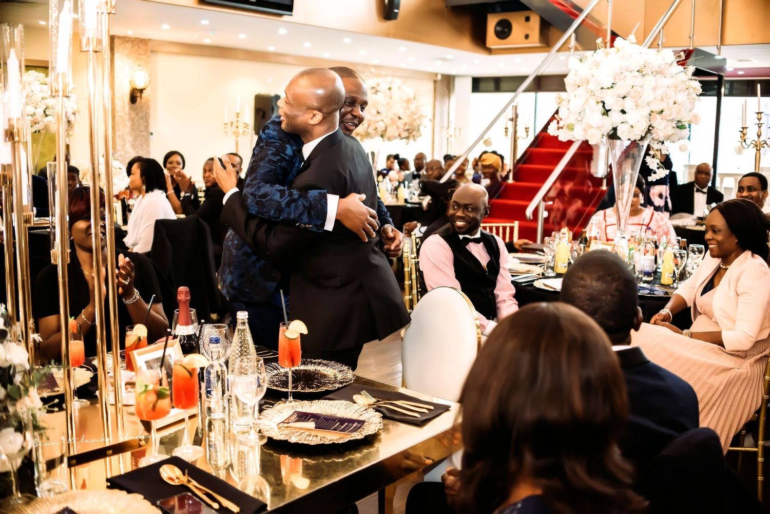 Elegant wedding reception setup with guests at decorated dinner tables, glittering crystal decorations and floral arrangements.